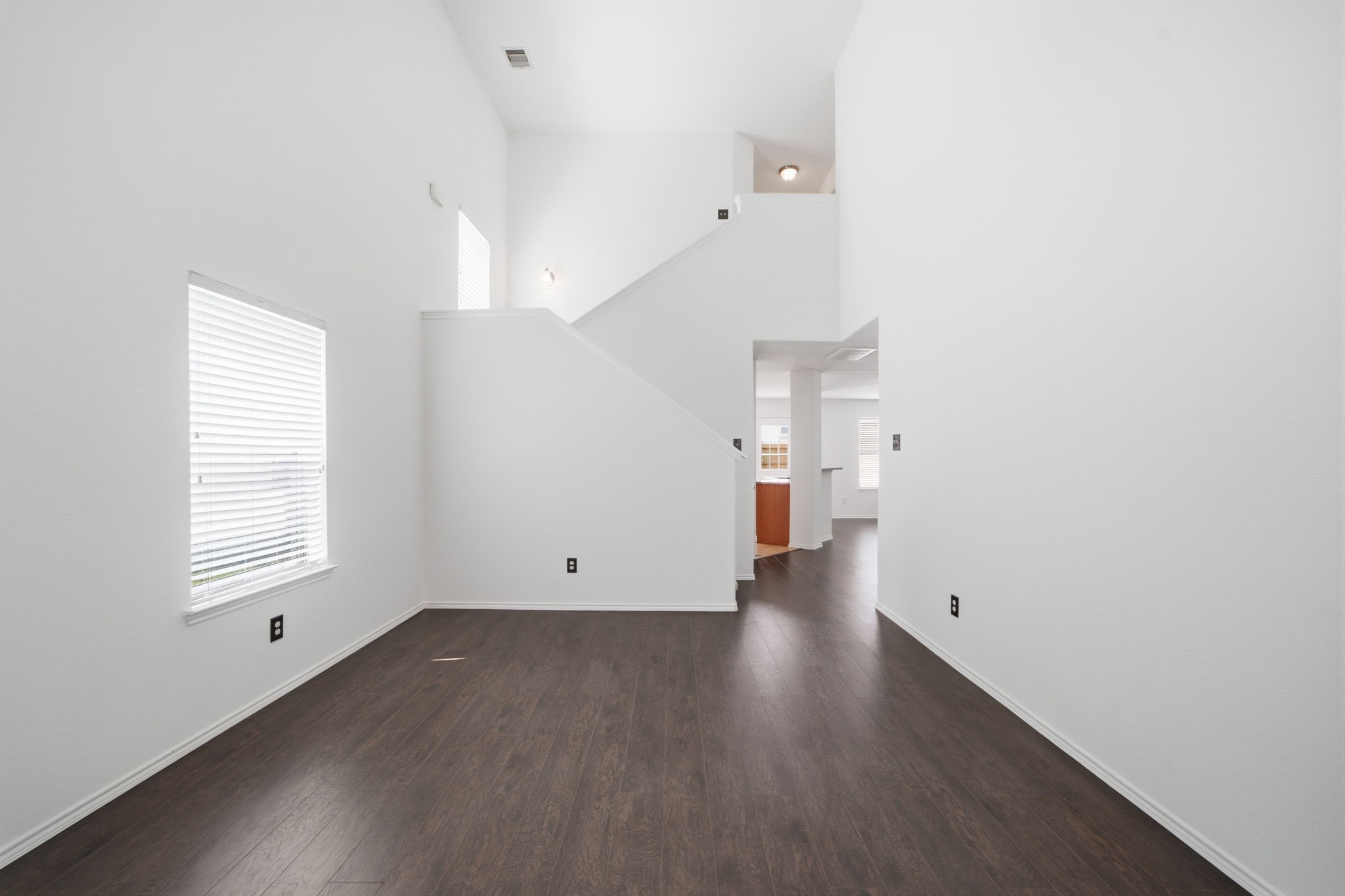 Soaring two-story ceilings and rich wood-look flooring enhance the open design of this flexible formal dining room. Convenient proximity to the kitchen makes hosting and entertaining seamless.