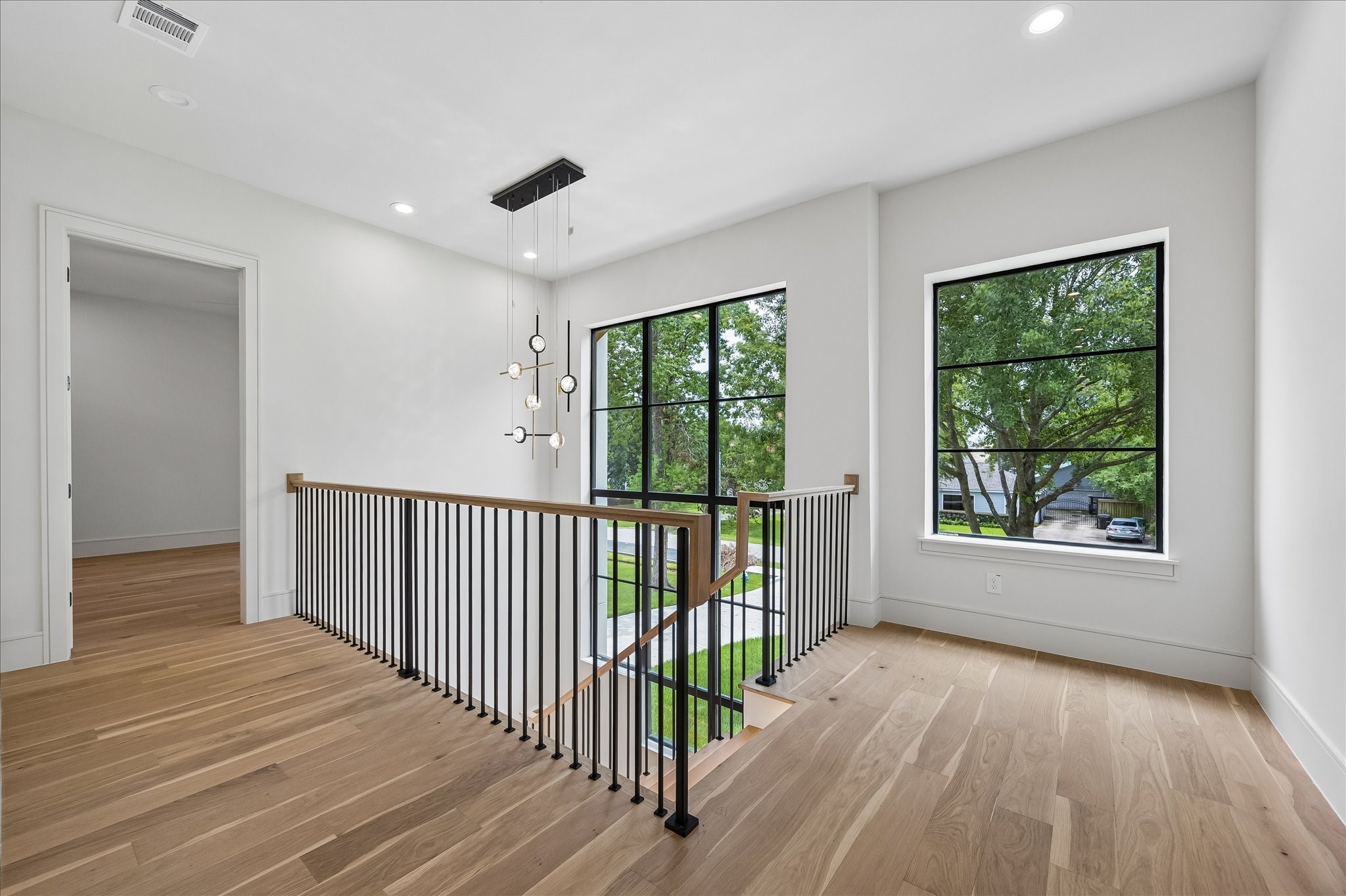 A striking two story staircase is framed by a custom specialty window unit - lifted into place by crane - that fills the landing with natural light. LED lighting and custom fabricated stair nosing milled from the flooring itself pair with a white oak handrail and metal balusters and posts for a clean architectural statement. An open upper landing enhances the homes airy, connected design.