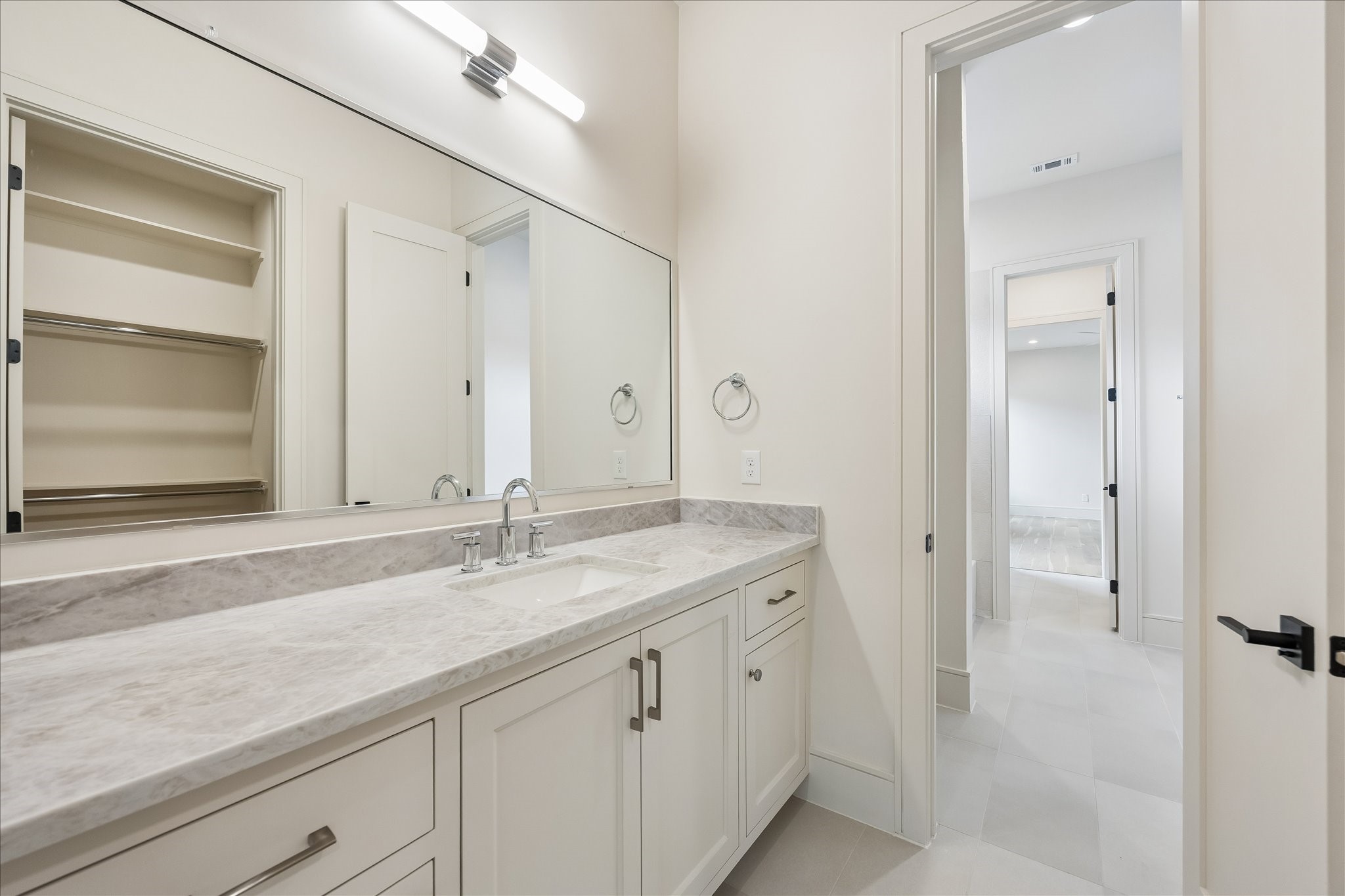 Quartz countertops, generous vanity storage, and a spacious walk in closet create a functional ensuite designed for everyday comfort. Clean lines and timeless finishes offer a bright, polished look that complements the adjoining bedroom.