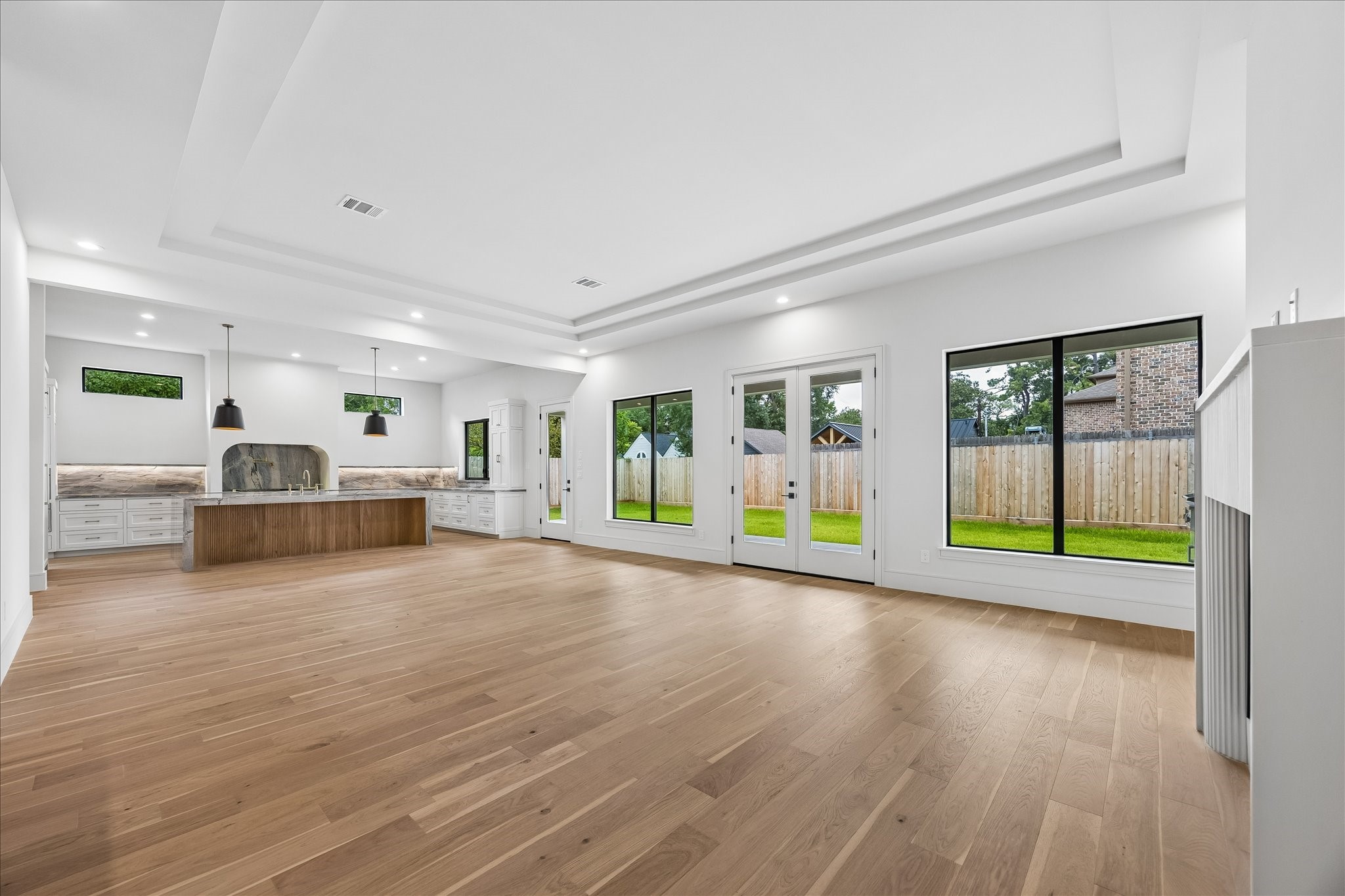 Vaulted tray ceilings and walls of windows fill the open living spaces with natural light while creating a seamless connection to the covered patio and backyard. Thoughtfully designed sightlines keep the kitchen, dining, and living areas connected without sacrificing a sense of scale.