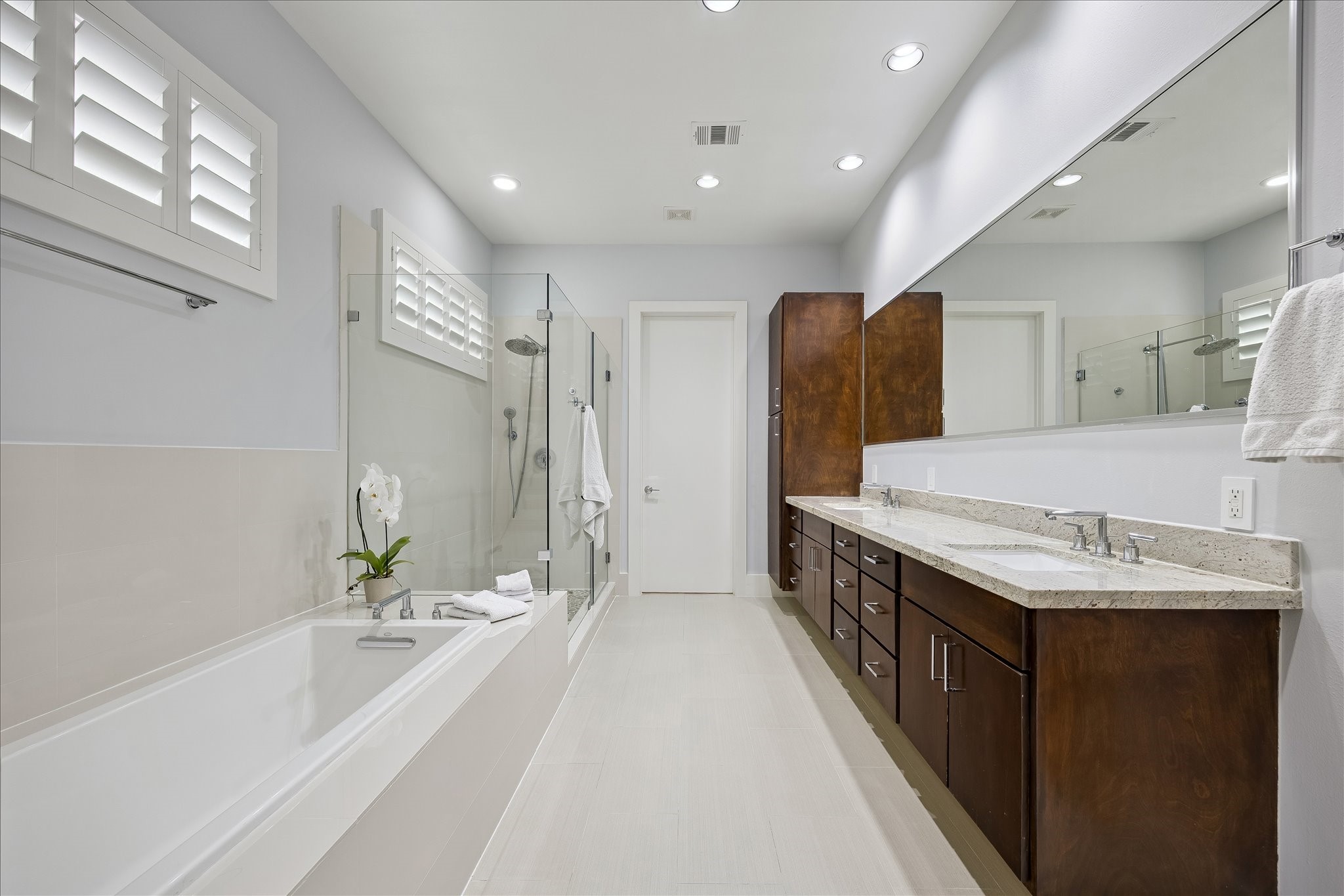 Luxurious PRIVATE BATH with dual sinks, a seamless glass shower and large soaking tub.