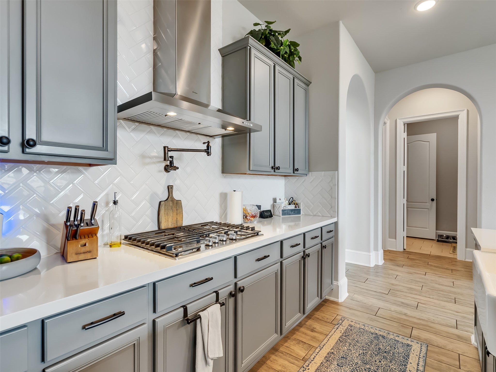Stylish backsplash and gas cooktop with adjacent pot-filler faucet.