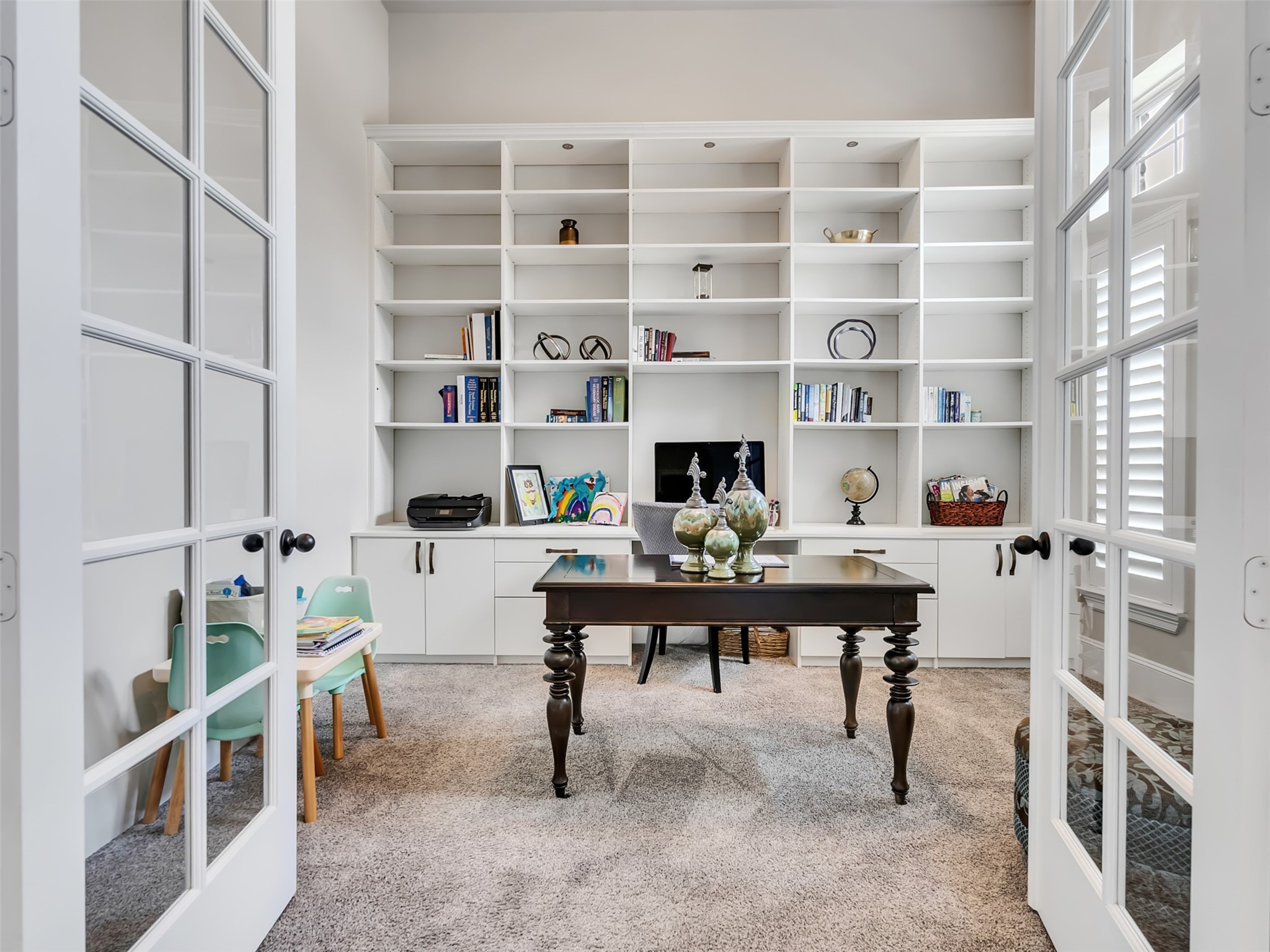 Home office with French doors and built-in bookshelves along with natural lighting. Home office with French doors and built-in bookshelves along with natural lighting.