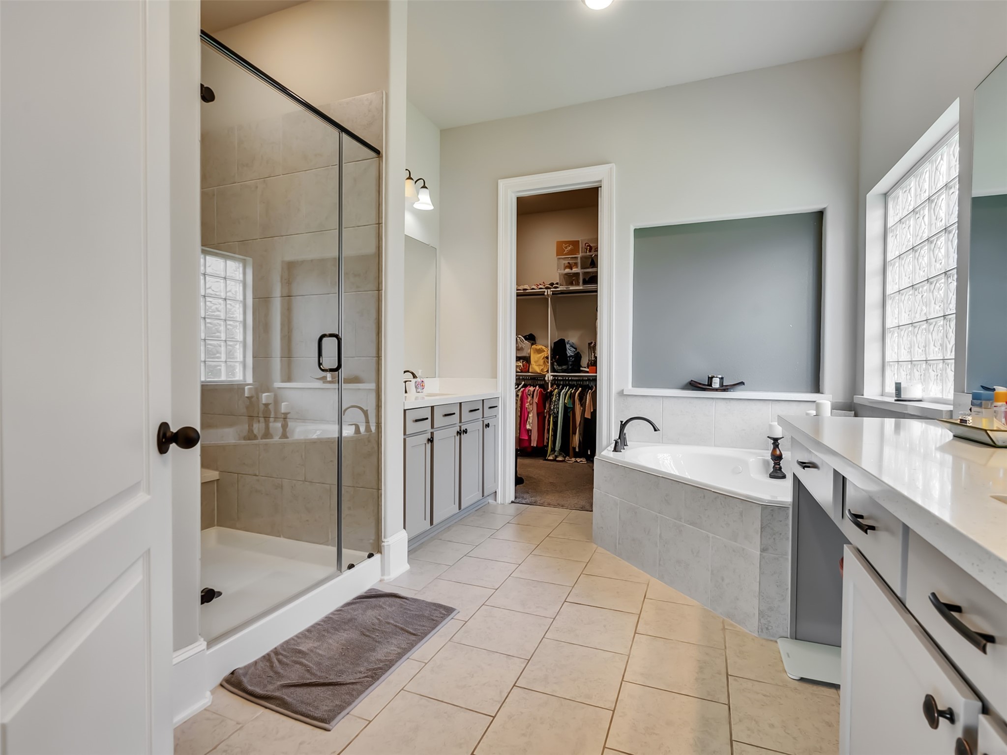 Glass enclosed shower, jacuzzi tub, and dual vanities make this Primary bathroom special.