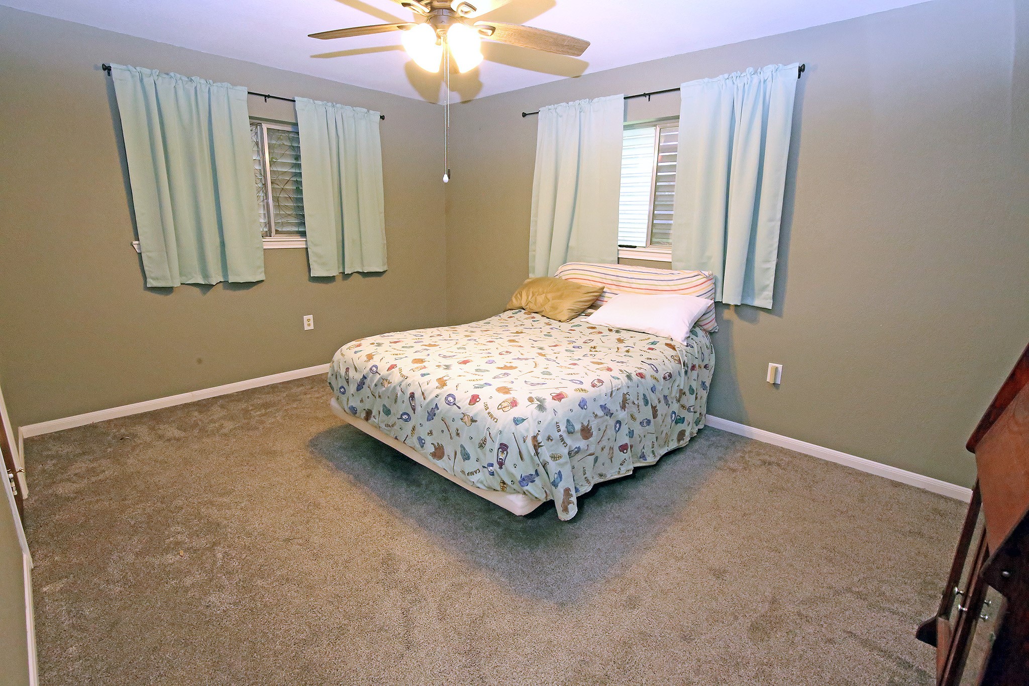 Experience comfort in this inviting primary bedroom, featuring soft carpet, ample natural light, and a ceiling fan for year-round comfort.
