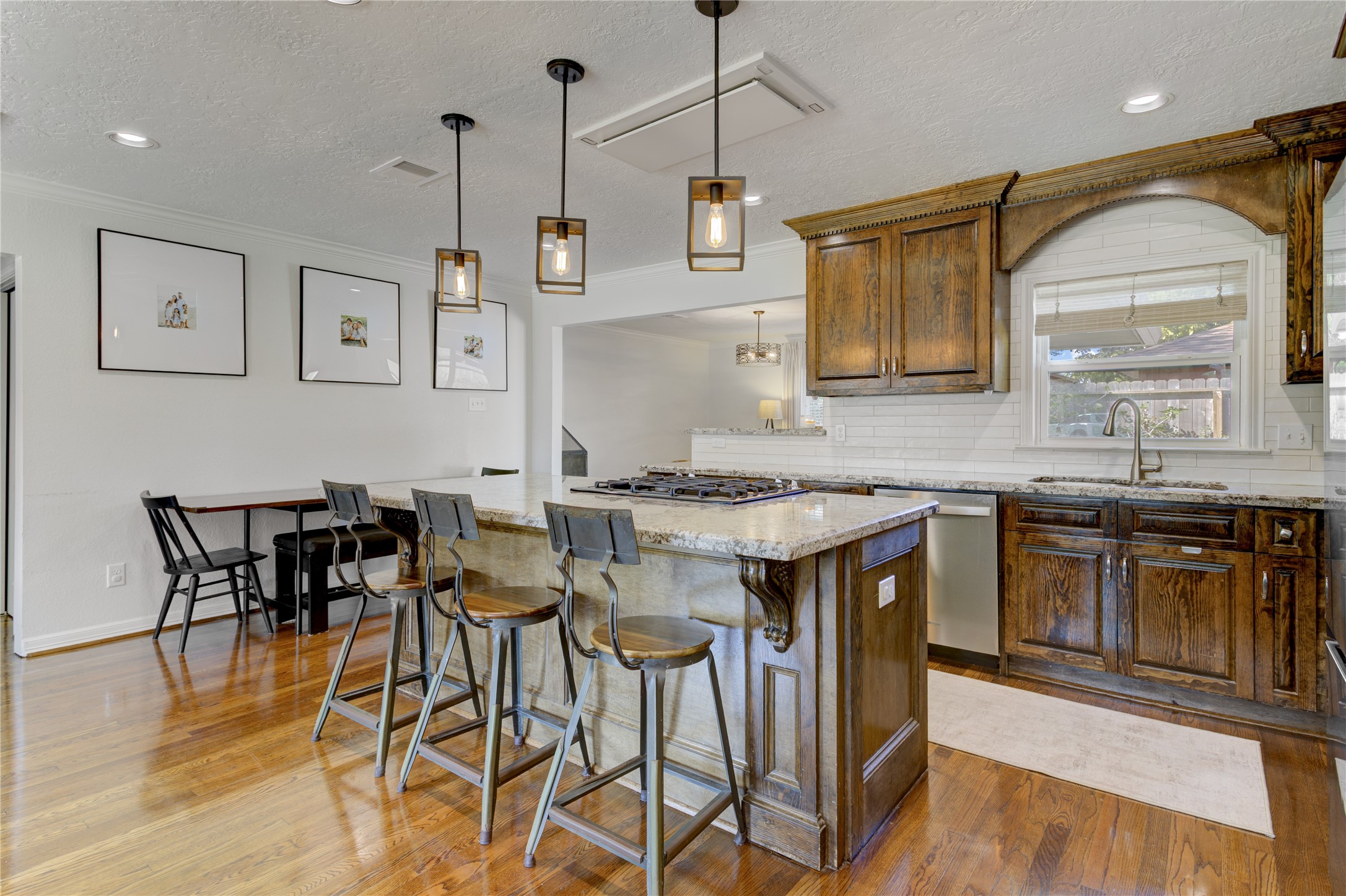 The kitchen offers bartop seating at the island, stainless steel gas range, and low-profile ceiling vent hood.