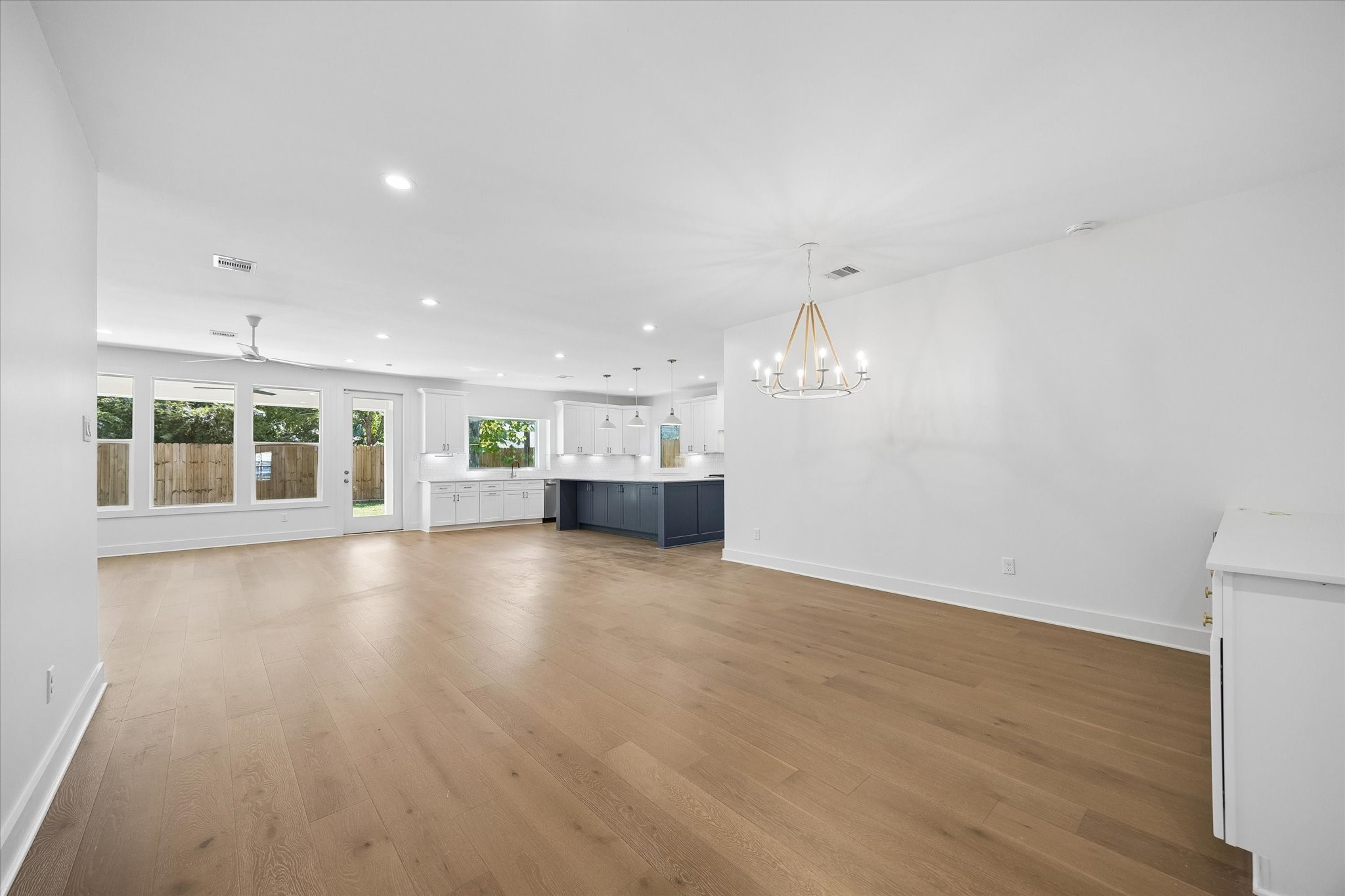 This view from the front entry shows off the open-concept living space. Crisp white walls and gleaming wood floors create a blank canvas, allowing you to make this home your perfect retreat.
