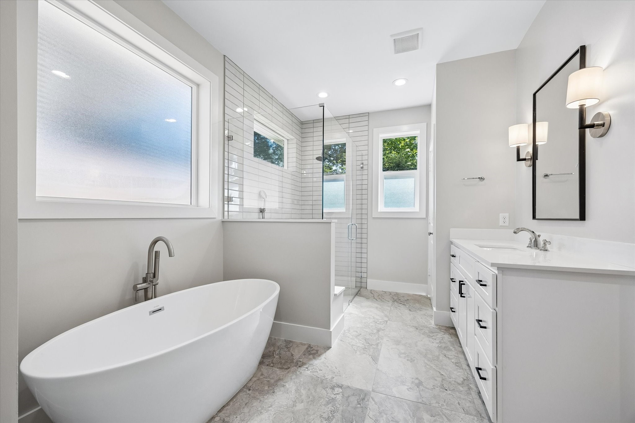 The primary bathroom offers a luxurious retreat with a sleek freestanding tub and a spacious walk-in shower with fashionable tile work.