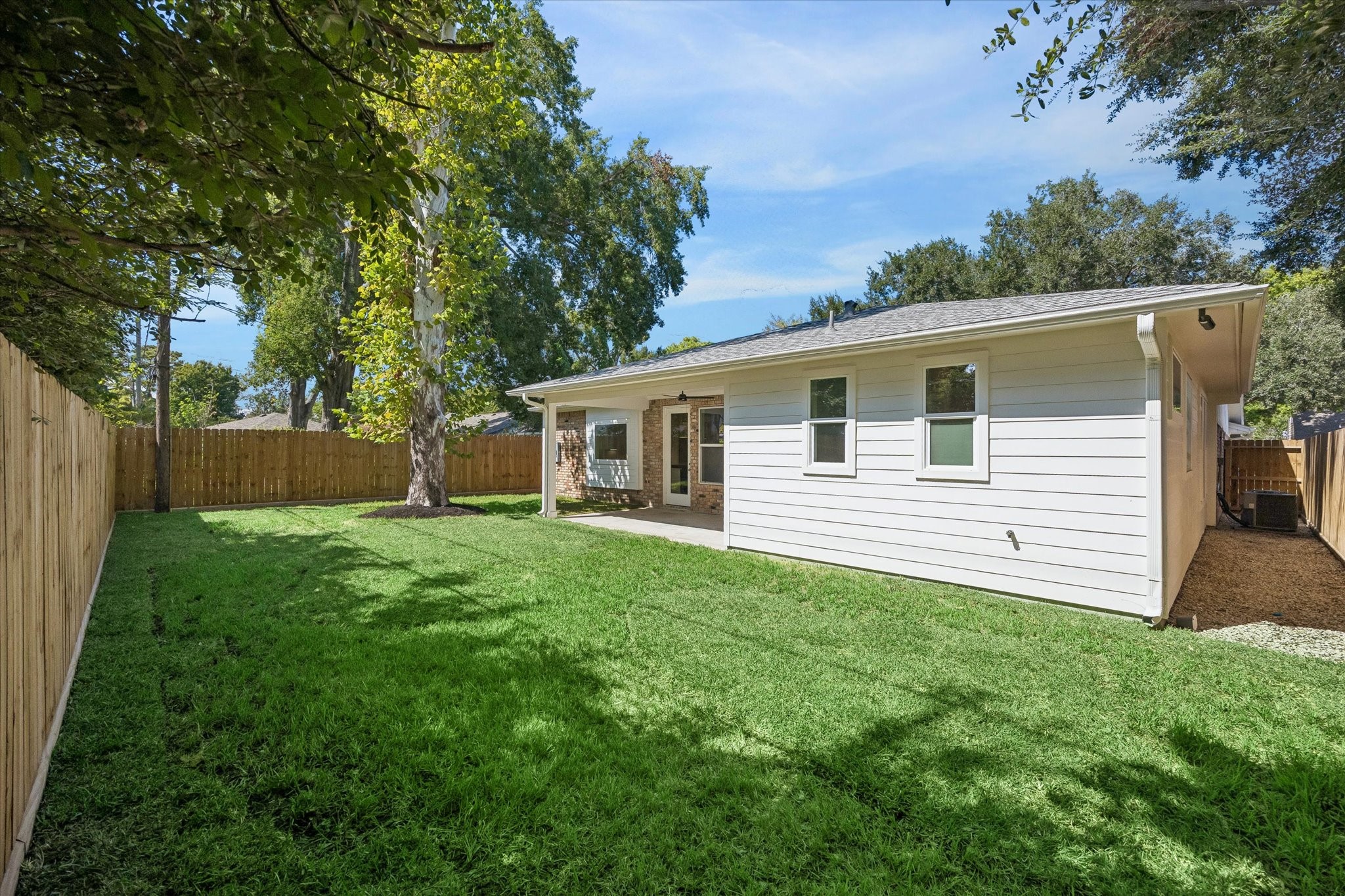 The large tree provides natural shade, enhancing the yard's appeal. Whether you envision a lush garden, play area, or outdoor dining spot, this backyard can accommodate your lifestyle needs.