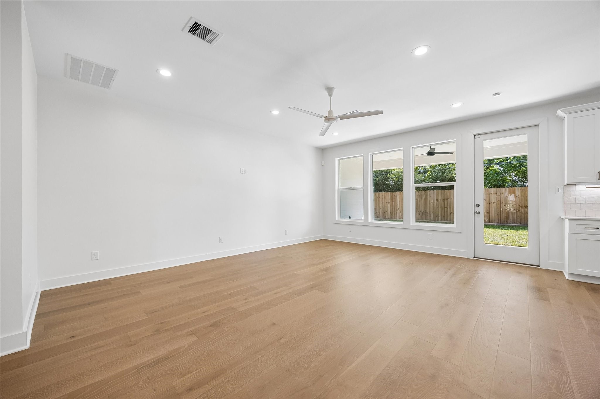 The living room boasts a clean, contemporary design with expansive windows that brighten the space. The open layout is perfect for family activities and entertaining, with direct access to the backyard enhancing its functionality for both daily living and gatherings.