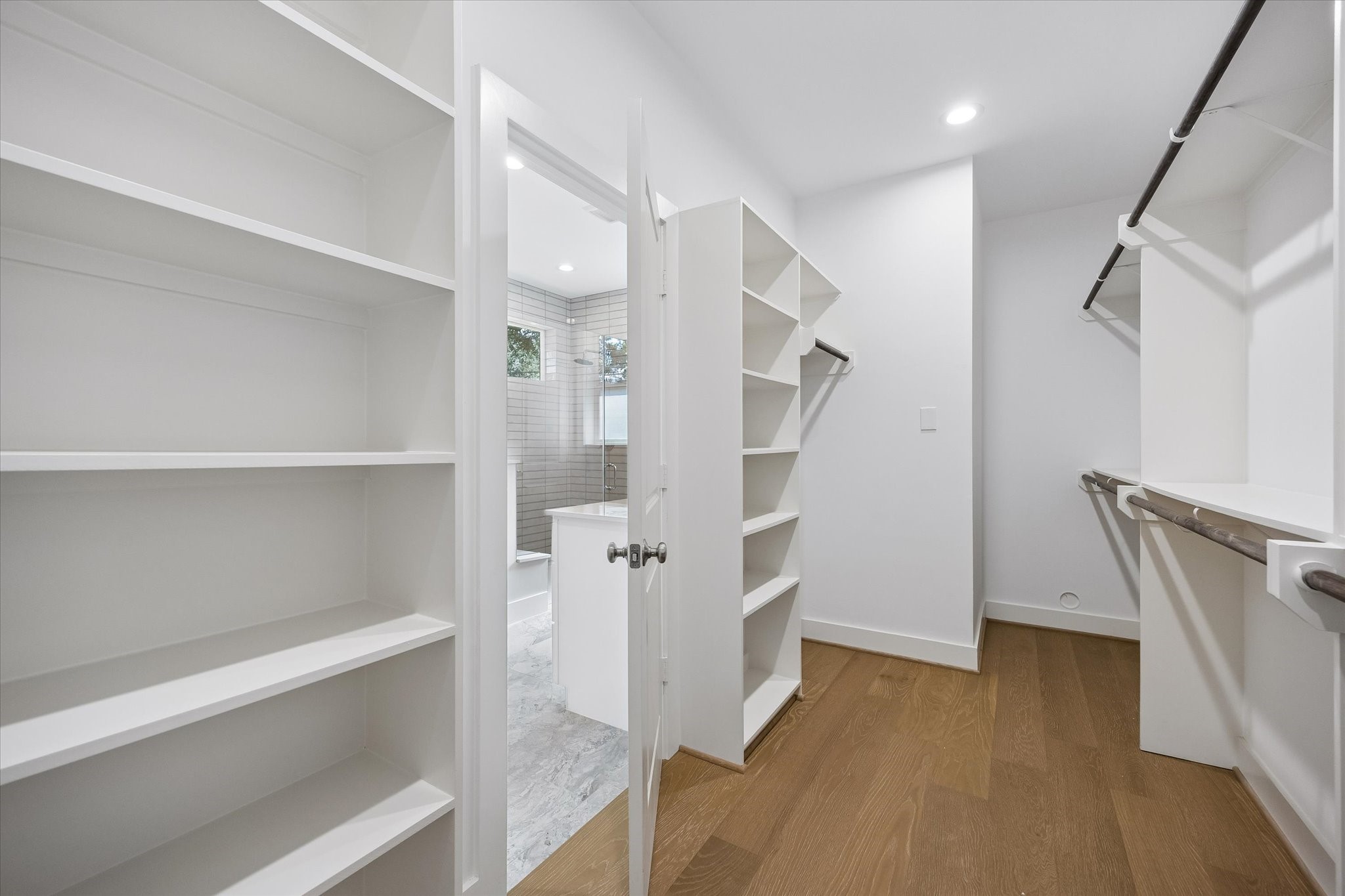 The primary bedroom closet boasts ample storage with built-in shelving and extensive hanging space, ensuring organization is effortless. Its spacious design allows for easy access and arrangement of clothing and accessories.