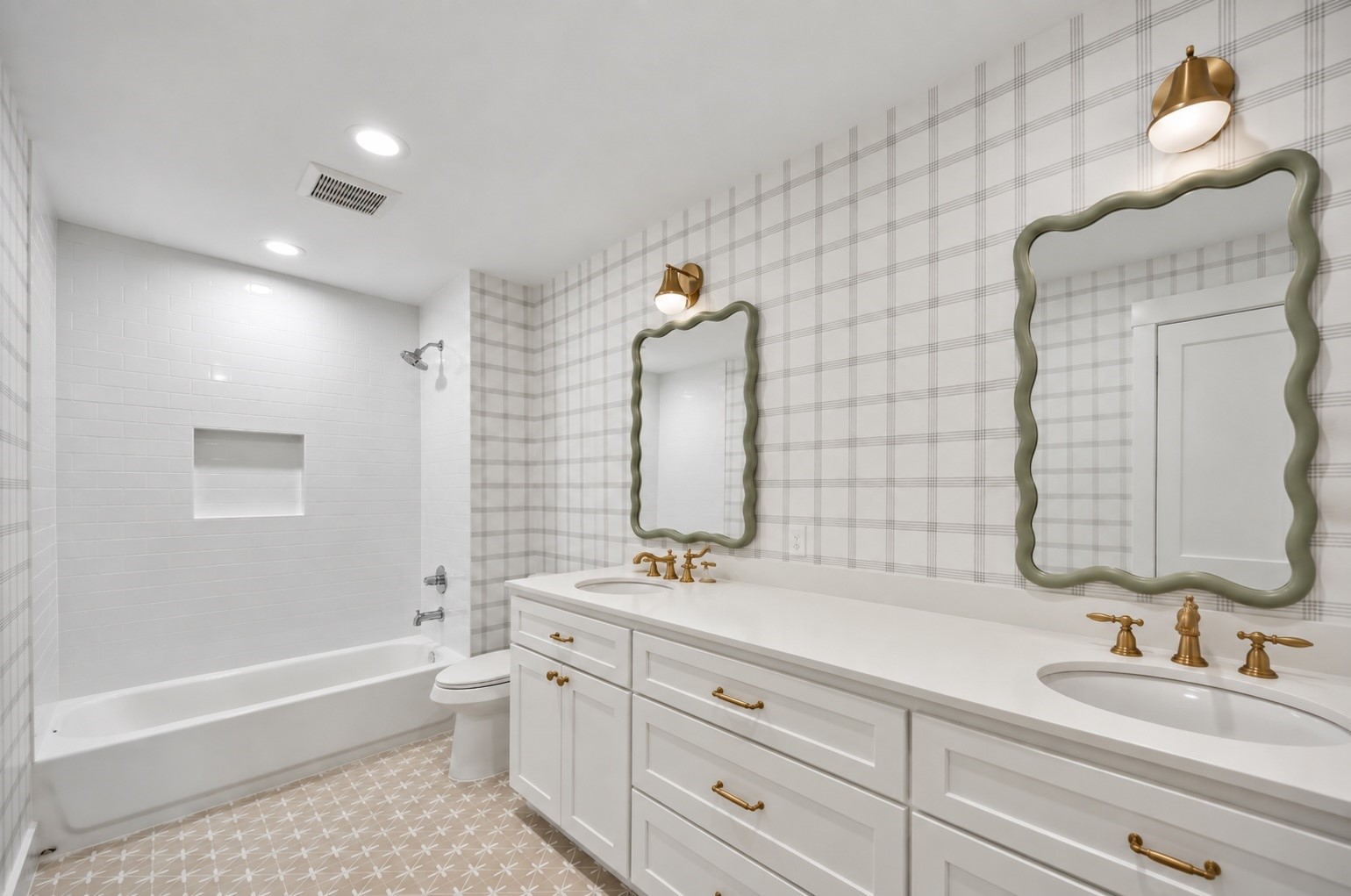 This secondary bathroom, located near the three additional bedrooms, features dual sinks with stylish framed mirrors, providing ample space for shared use. The elegant fixtures complement the clean, white cabinetry, while the patterned floor tiles add a touch of charm. The combination of a bathtub and a spacious shower ensures both convenience and comfort.