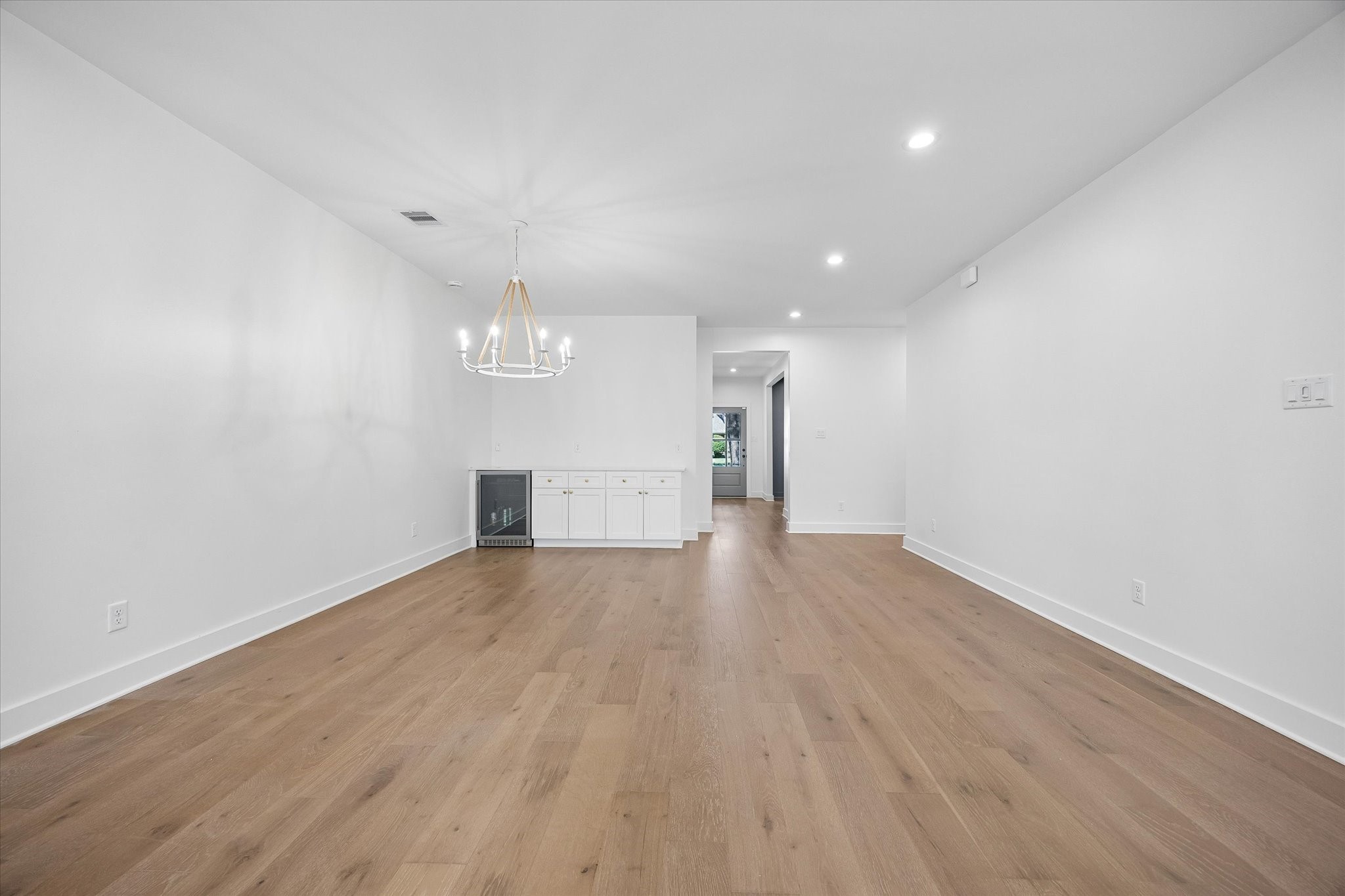 The dining room features a sophisticated chandelier, providing a refined focal point. Adjacent to the dining area, you'll find built-in cabinets offering ample storage and a dedicated section perfect for a wine fridge or beverage storage, enhancing the functionality and appeal of this space.