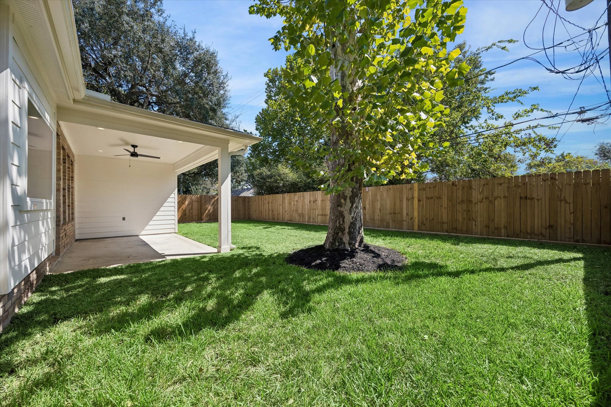 The backyard offers a spacious canvas ready for your personal touch. With a covered patio area featuring a ceiling fan, this space is perfect for outdoor relaxation and gatherings.