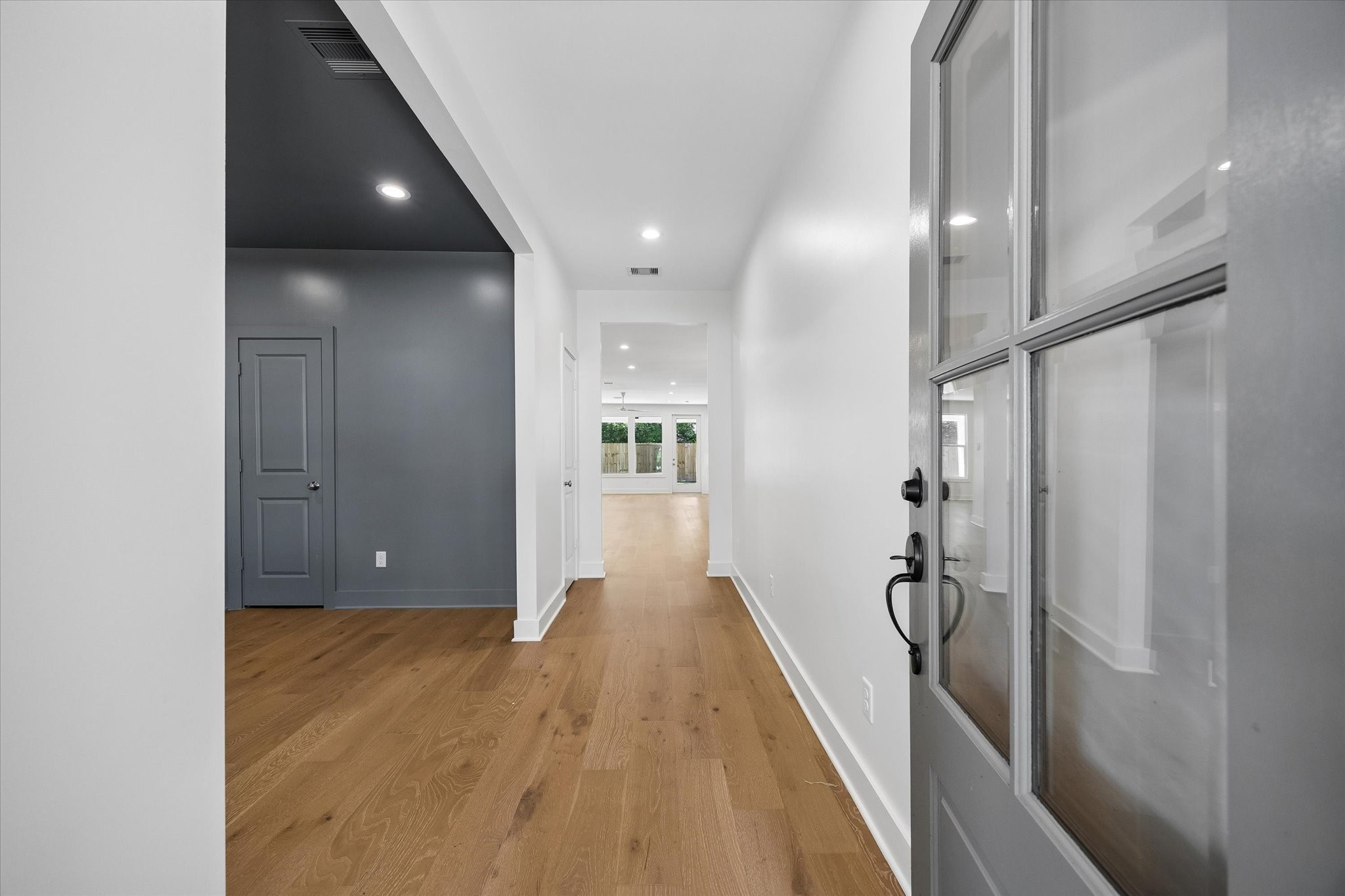 Warm wood flooring draws the eye from the entry through the home, creating a clean sightline toward the main living areas and backyard beyond.