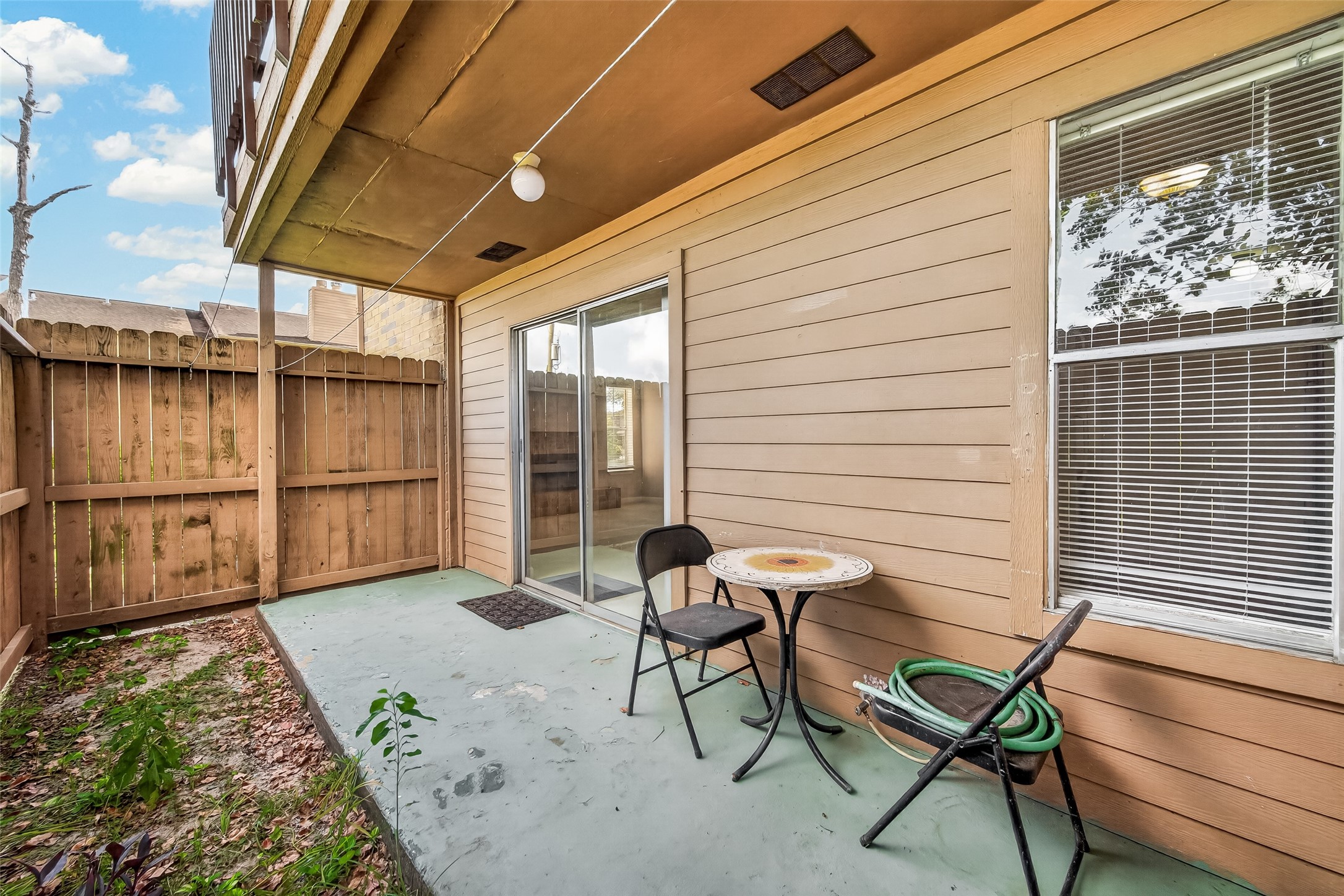 Charming patio space with privacy fencing, offering a cozy spot for relaxation or outdoor dining, complete with sliding doors for easy indoor-outdoor access.