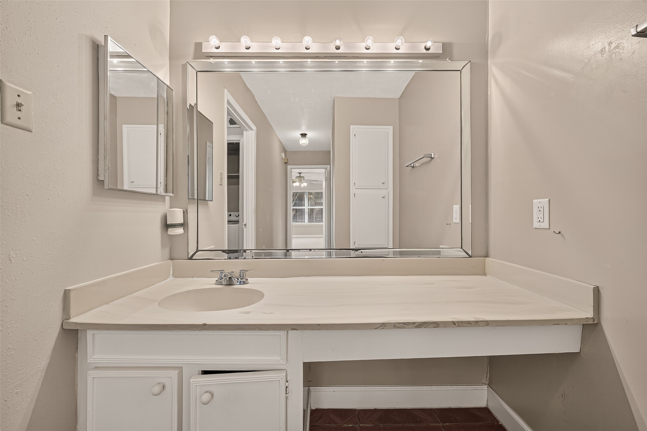 Spacious bathroom vanity with a large mirror and ample counter space, enhanced by soft lighting and neutral tones.