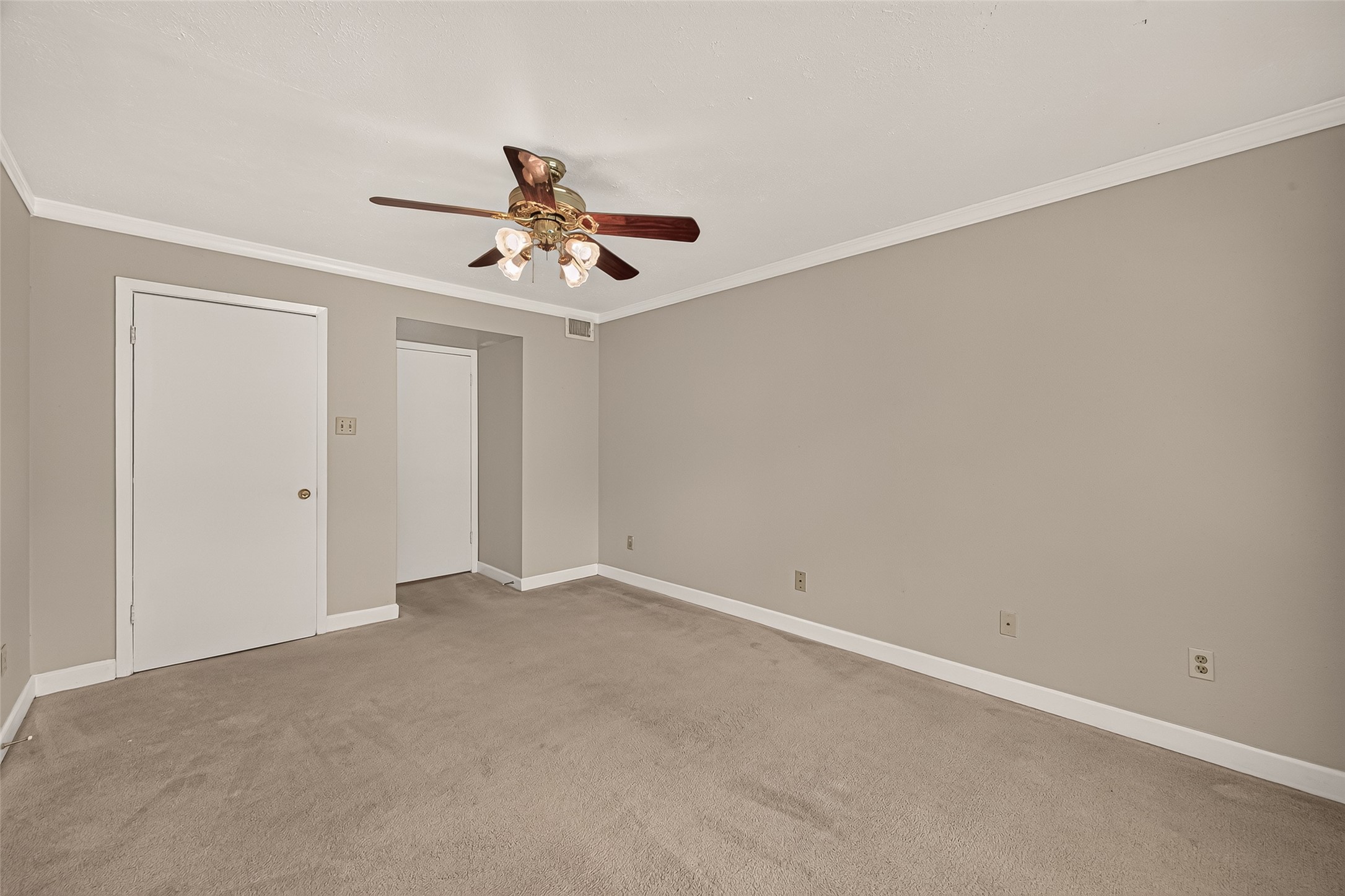 Spacious room with neutral tones, featuring a ceiling fan and ample natural light.