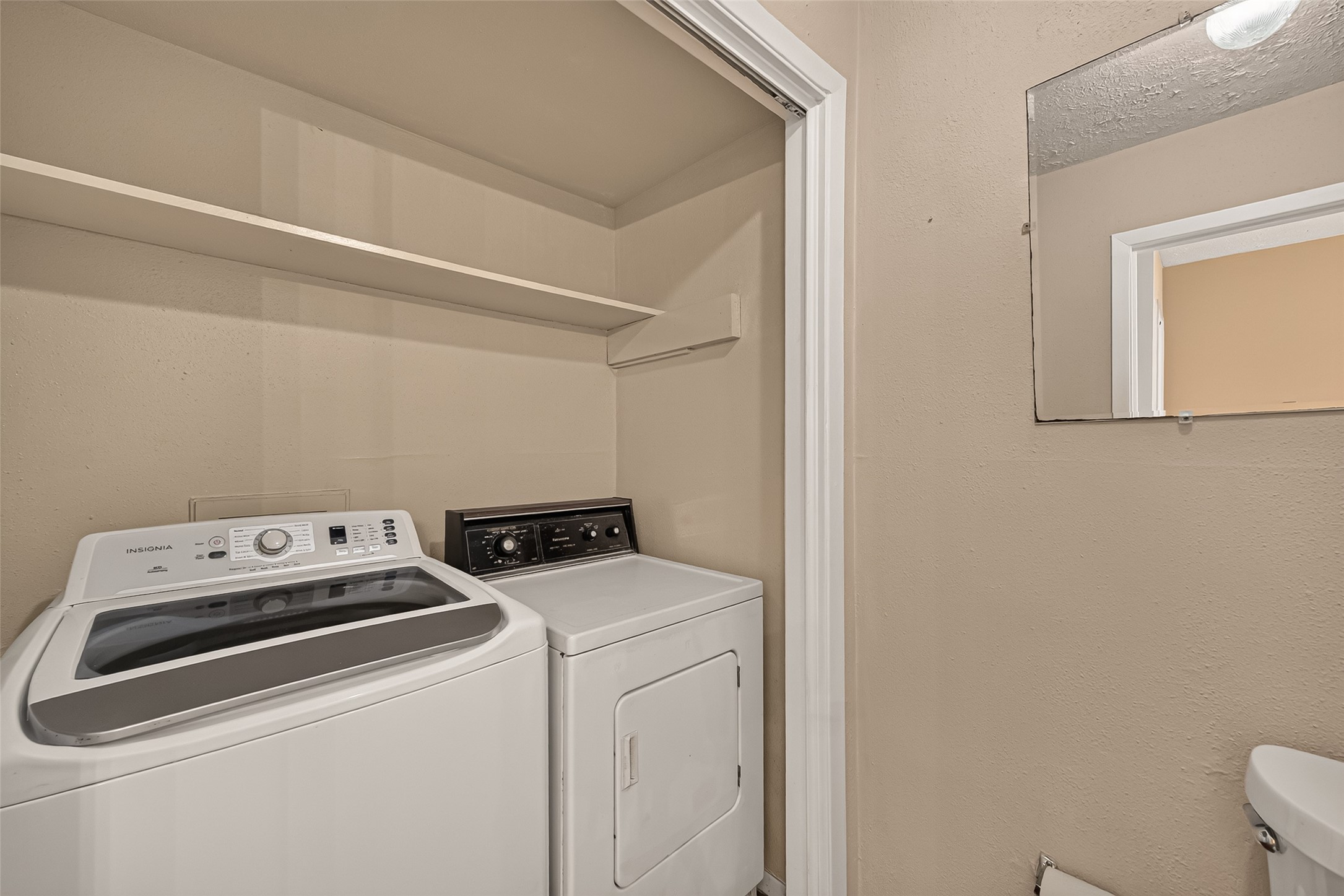 Convenient laundry area with washer and dryer, featuring overhead shelving for additional storage.
