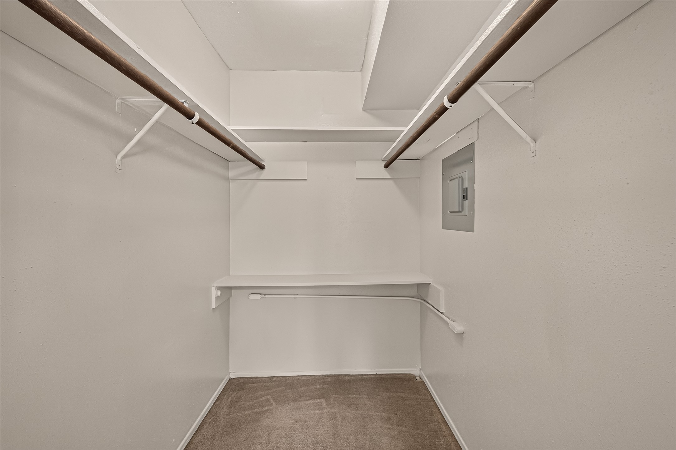 Spacious walk-in closet with dual hanging rods and a built-in shelf, perfect for organized storage.