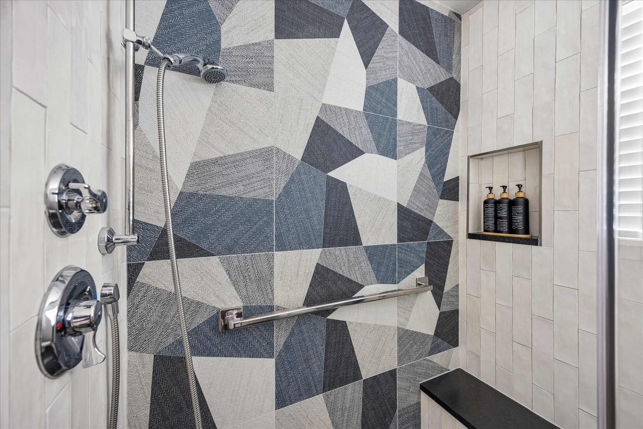 Striking geometric tile creates a beautiful focal point in the shower, complete with a built-in bench and recessed niche.