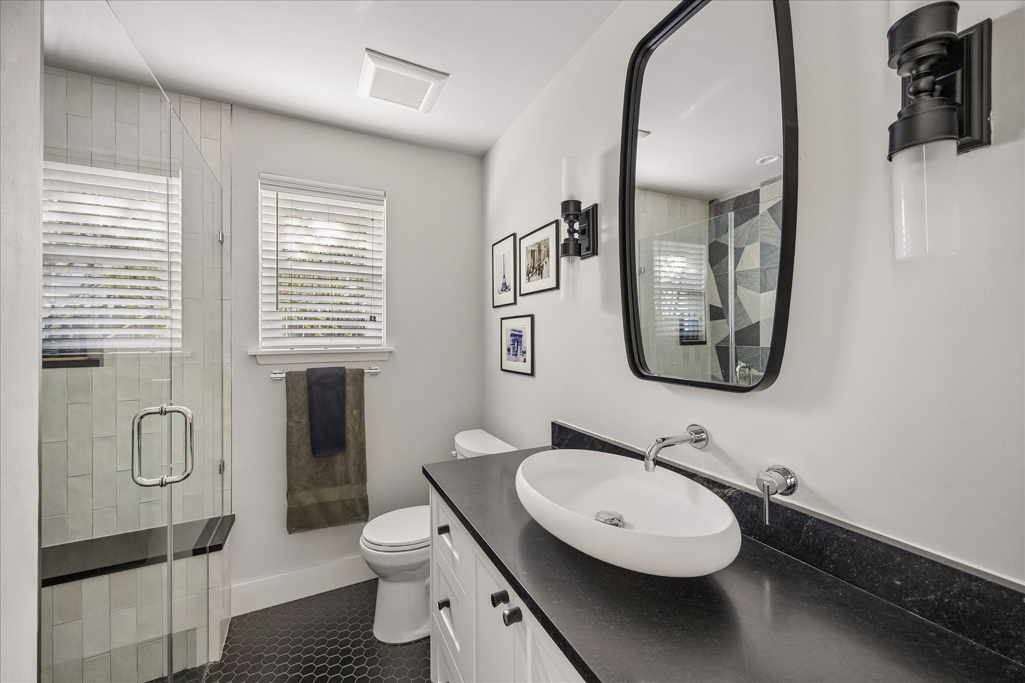 A contemporary vessel sink, wall-mounted faucet, and sleek black accents bring a sophisticated touch to the secondary bath.