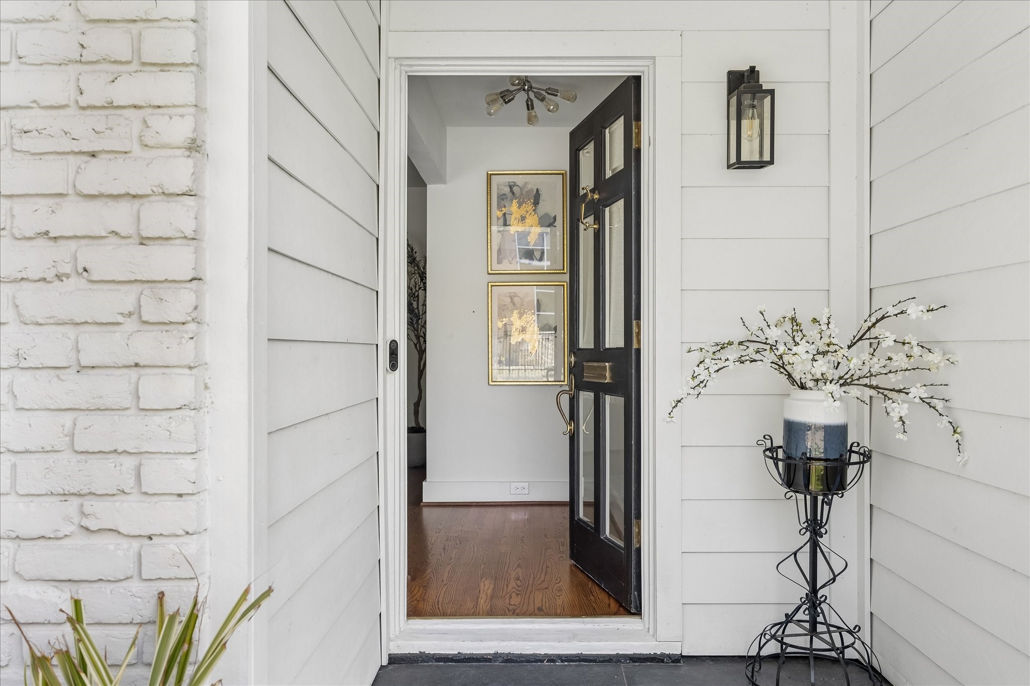 A handsome black front door, lantern-style lighting, and warm hardwood flooring just beyond offer a welcoming introduction. A handsome black front door, lantern-style lighting, and warm hardwood flooring just beyond offer a welcoming introduction.