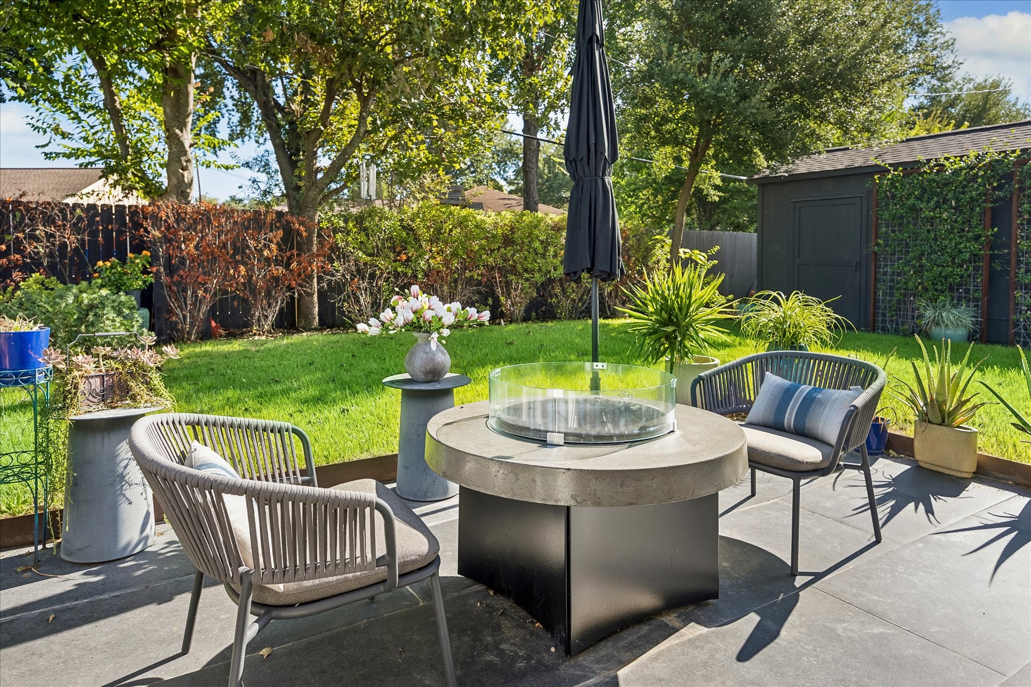 A lovely outdoor retreat featuring a spacious patio, lush lawn, and mature trees framed by thoughtfully maintained landscaping.