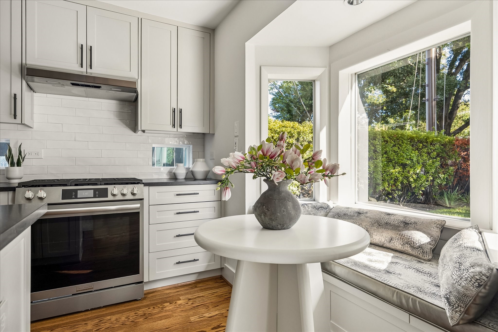 Stainless steel appliances, classic subway tile, and tailored cabinetry complement this sun-filled corner of the kitchen.