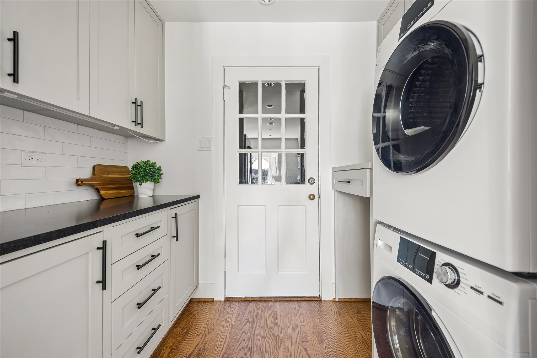 A thoughtfully appointed laundry room features stacked appliances, ample cabinetry, and convenient countertop space.