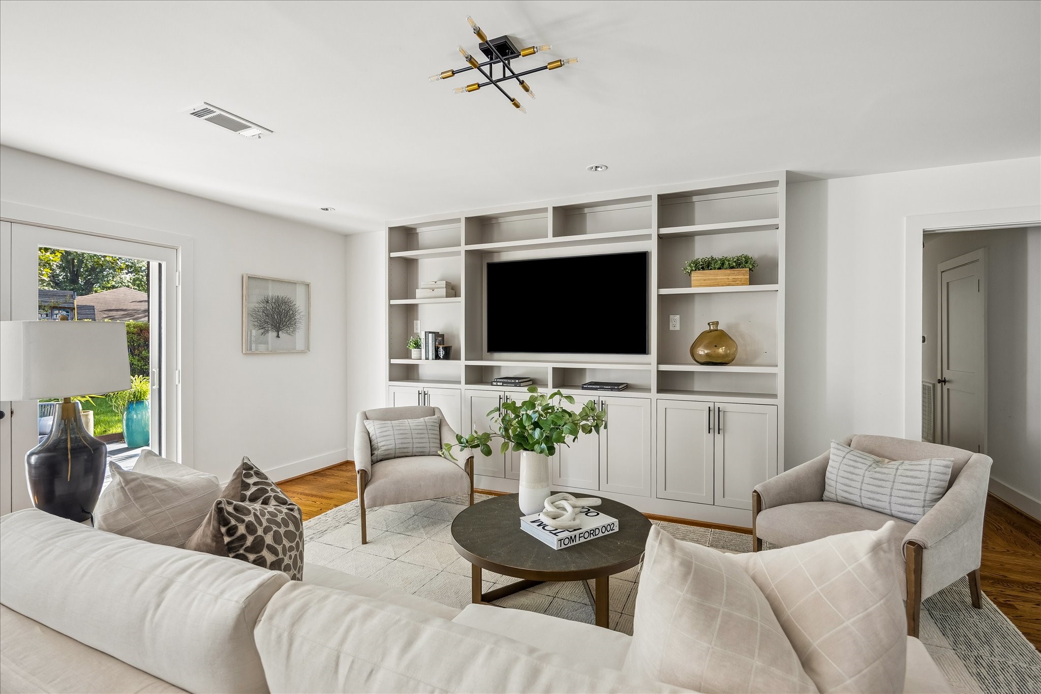 A beautifully integrated wall of custom cabinetry offers open shelving, concealed storage, and a dedicated media space.