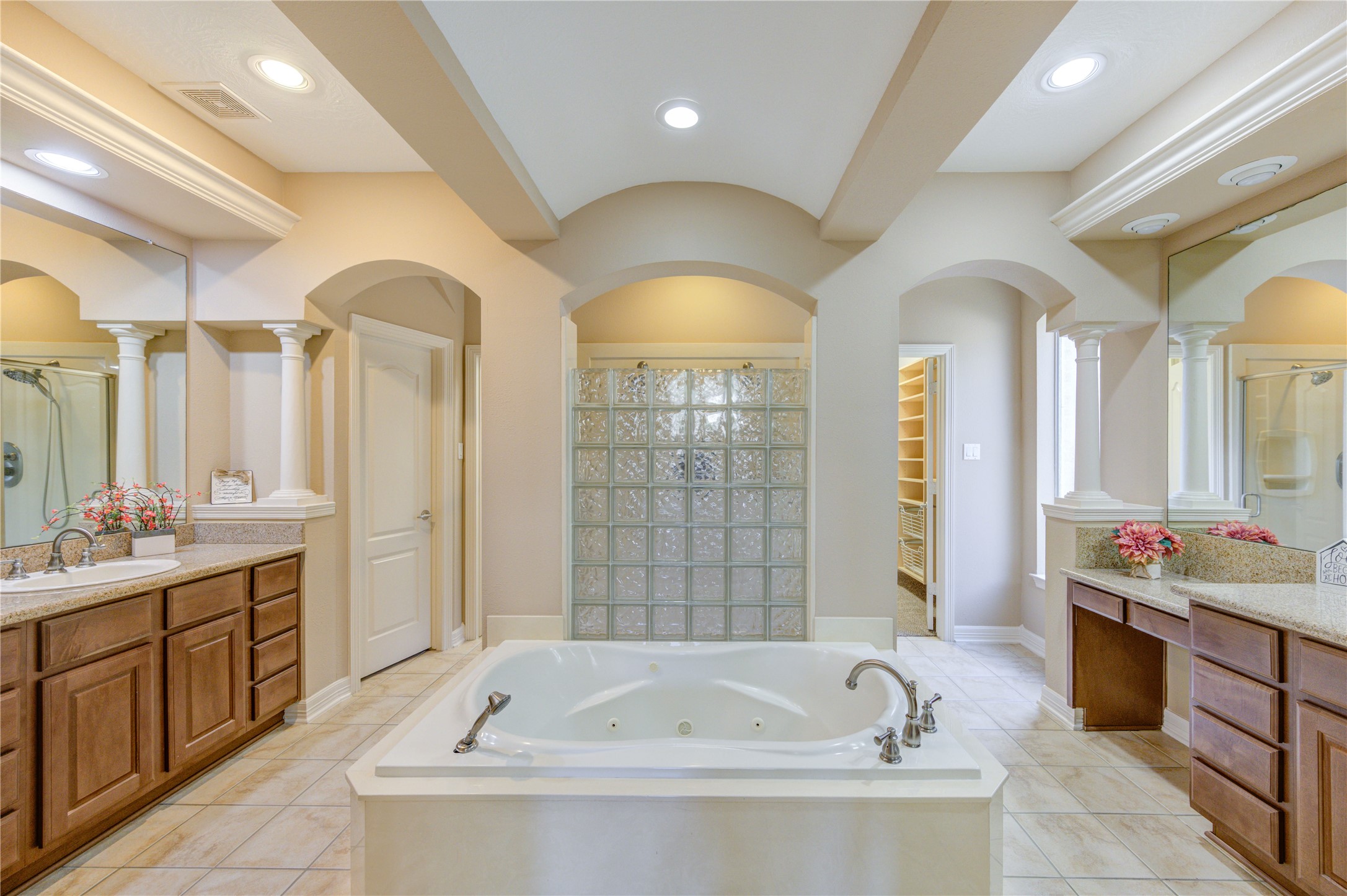 Luxurious primary bathroom with split vanities, featuring a spacious hers side with generous counter space and a separate his area for added convenience