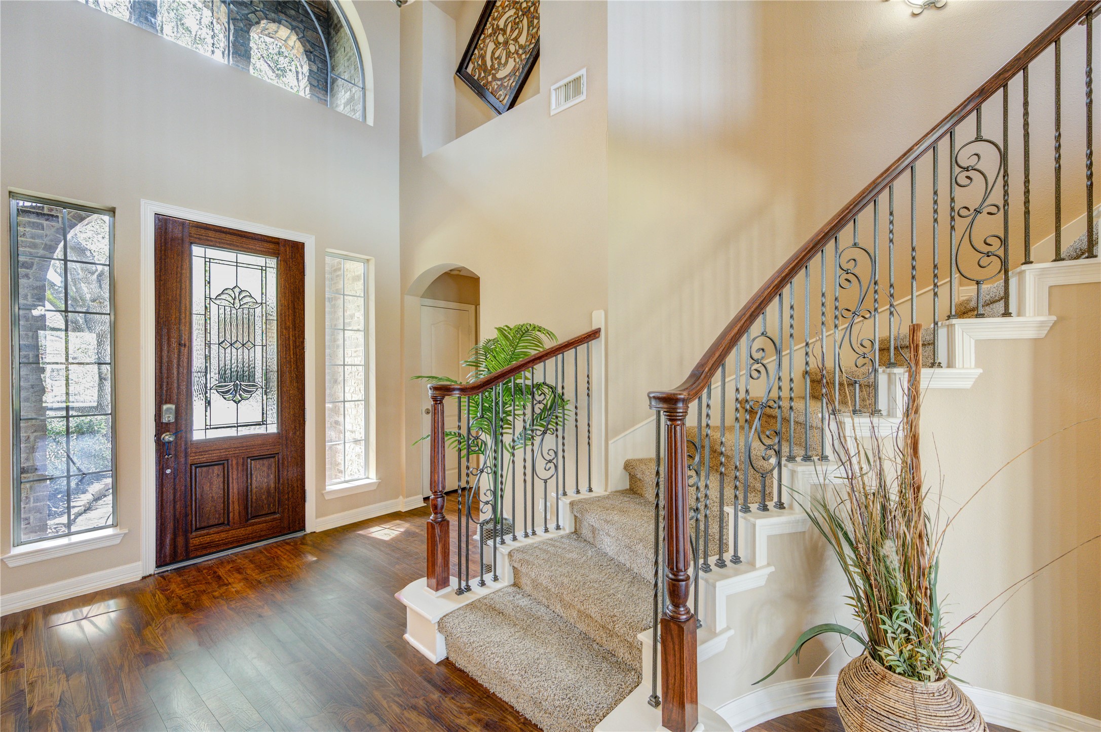 Open living space with a beautiful staircase and front entry view.
