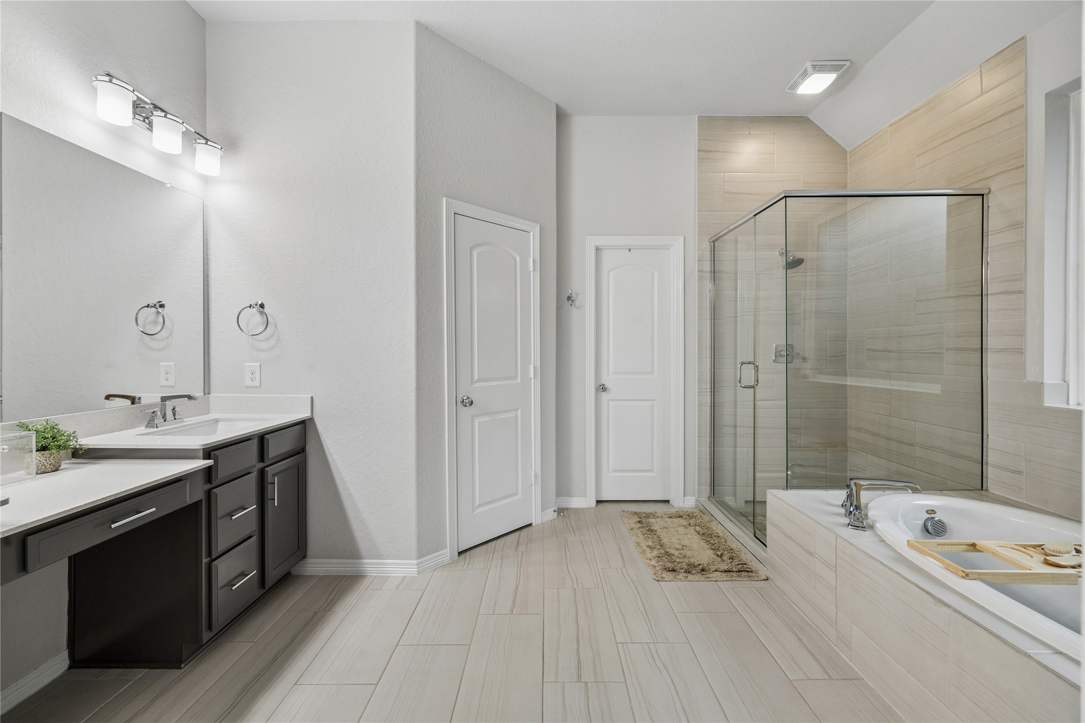 primary bath, dual quartz counters, vanity, organic tone porcelain tile floors, framed shower, large drop in tub.