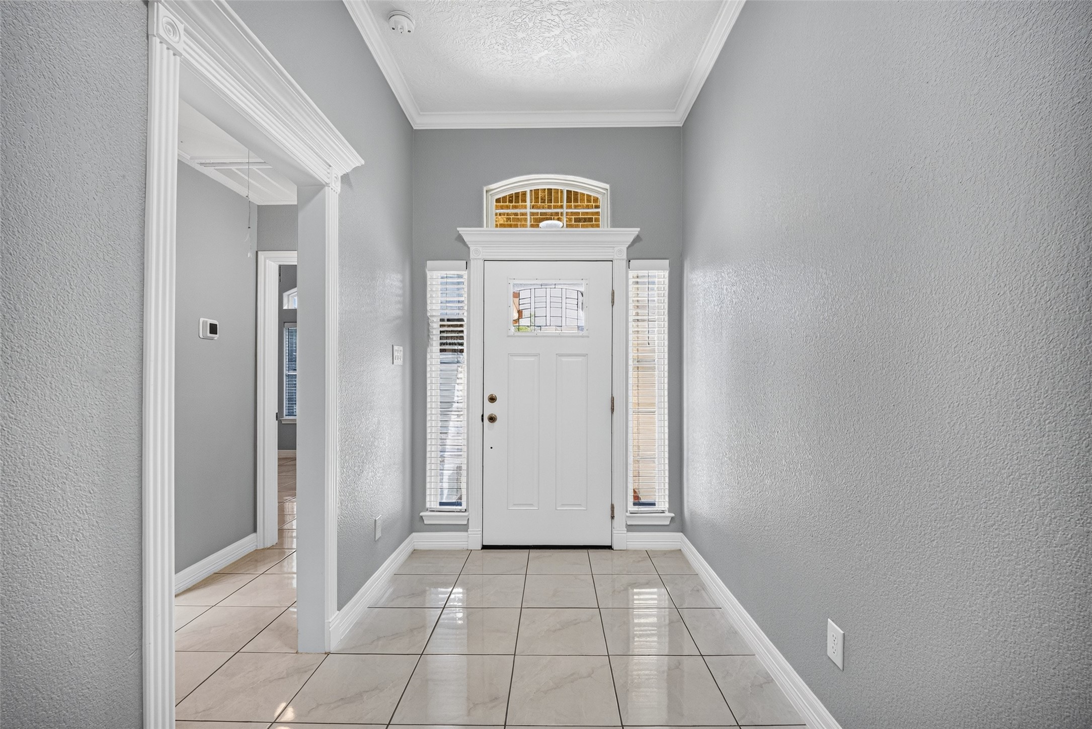 Bright and inviting entryway featuring elegant tile flooring, a charming white front door with sidelights, and a transom window for added natural light. Bright and inviting entryway featuring elegant tile flooring, a charming white front door with sidelights, and a transom window for added natural light.