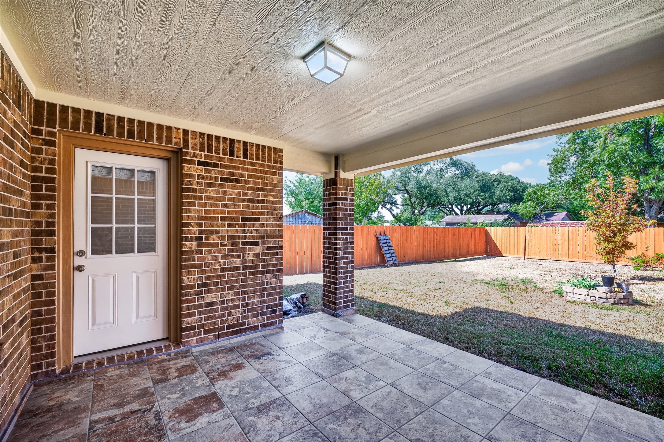 Charming covered patio with elegant brick walls and stylish tile flooring, perfect for outdoor relaxation and entertaining.