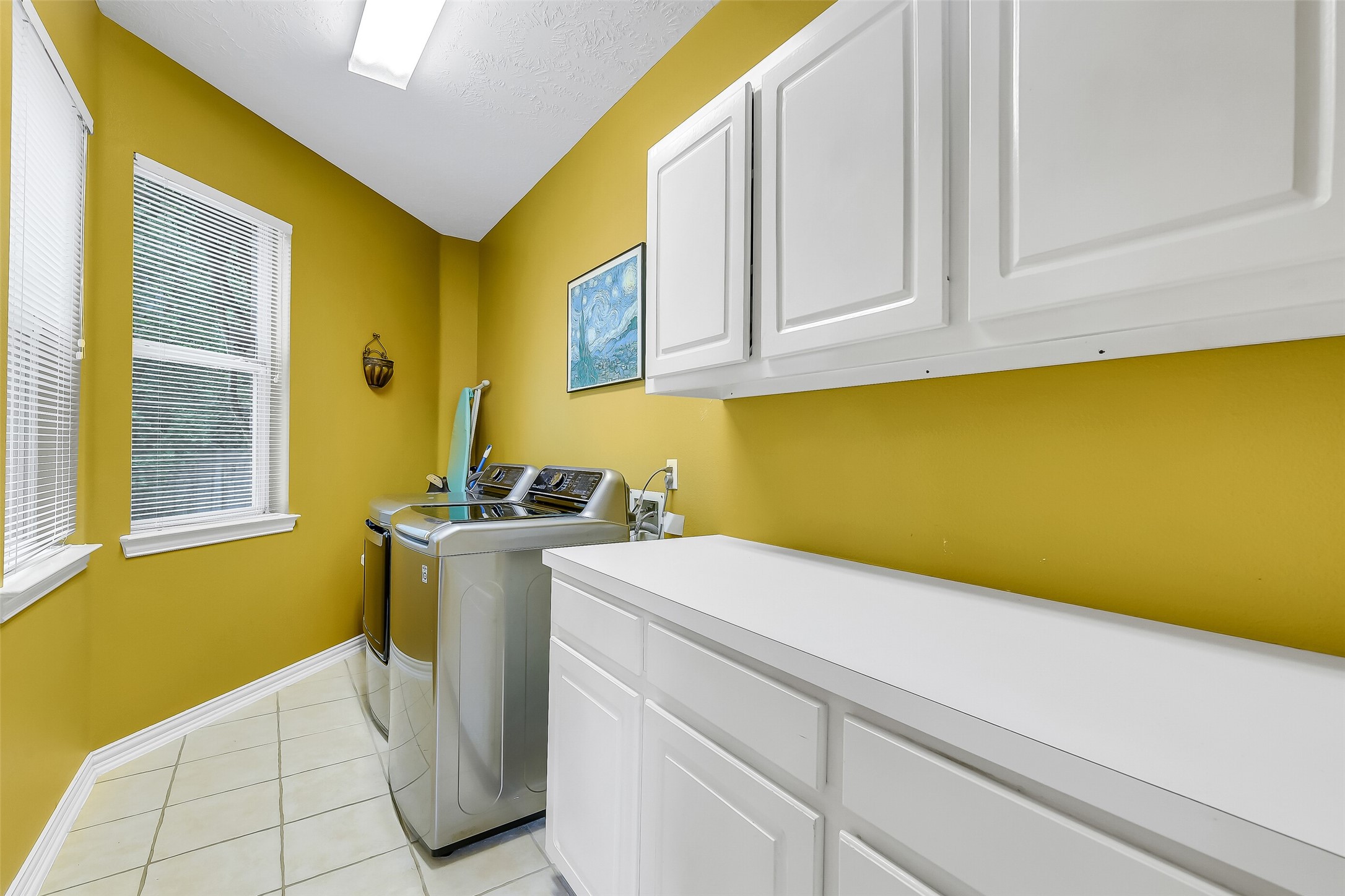 Bright and functional laundry room featuring ample cabinetry, modern appliances, and large windows for natural light.