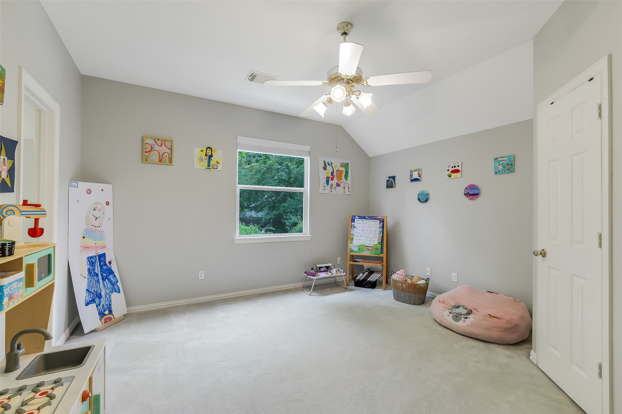 Bright and spacius bedroom with Jack and Jill bath featuring a ceiling fan, neutral walls, and a large window offering plenty of natural light. Ideal for creativity and relaxation.