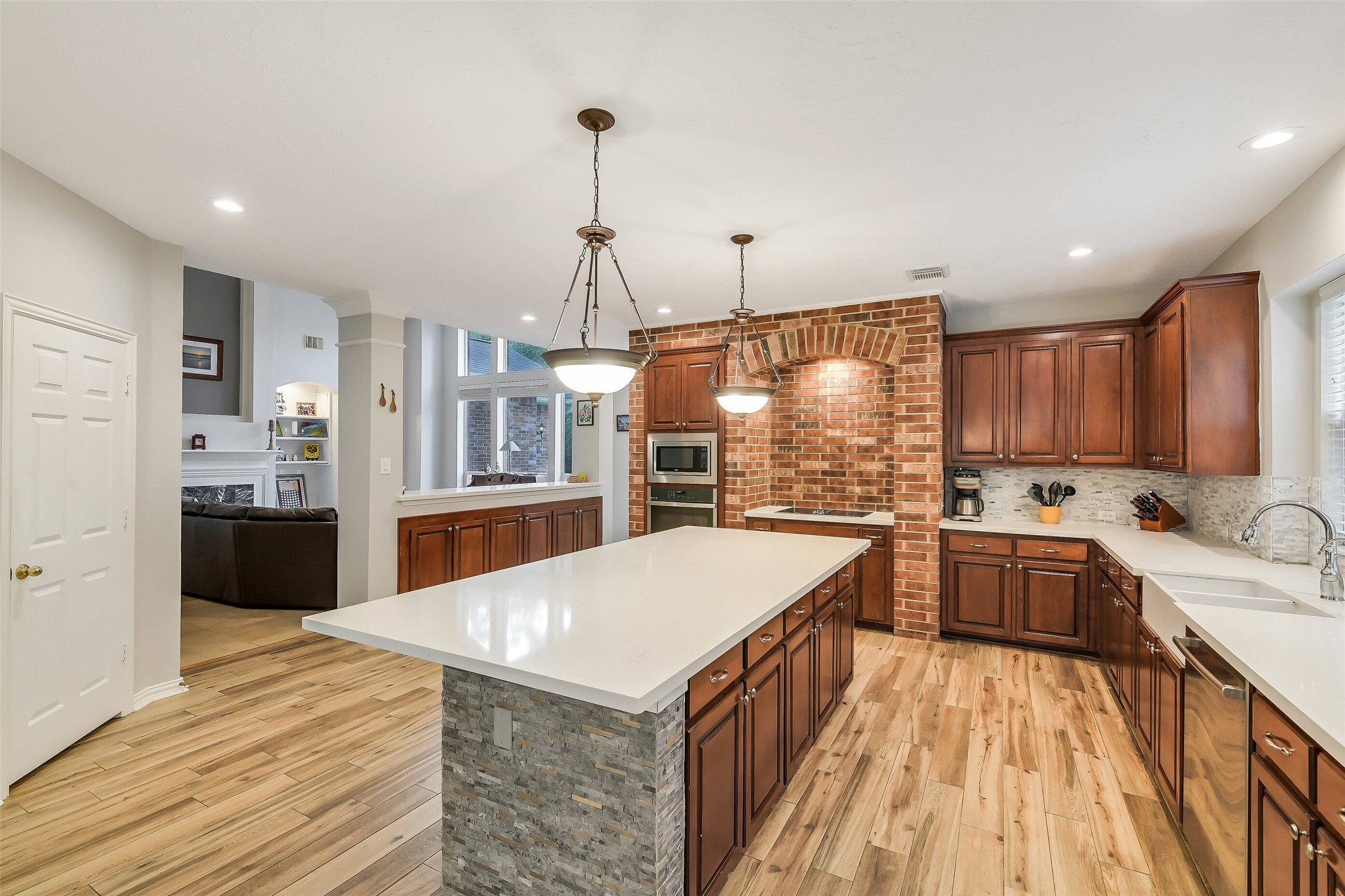 Spacious kitchen with elegant wooden cabinetry, a large central island, and stylish brick accents, perfect for entertaining.