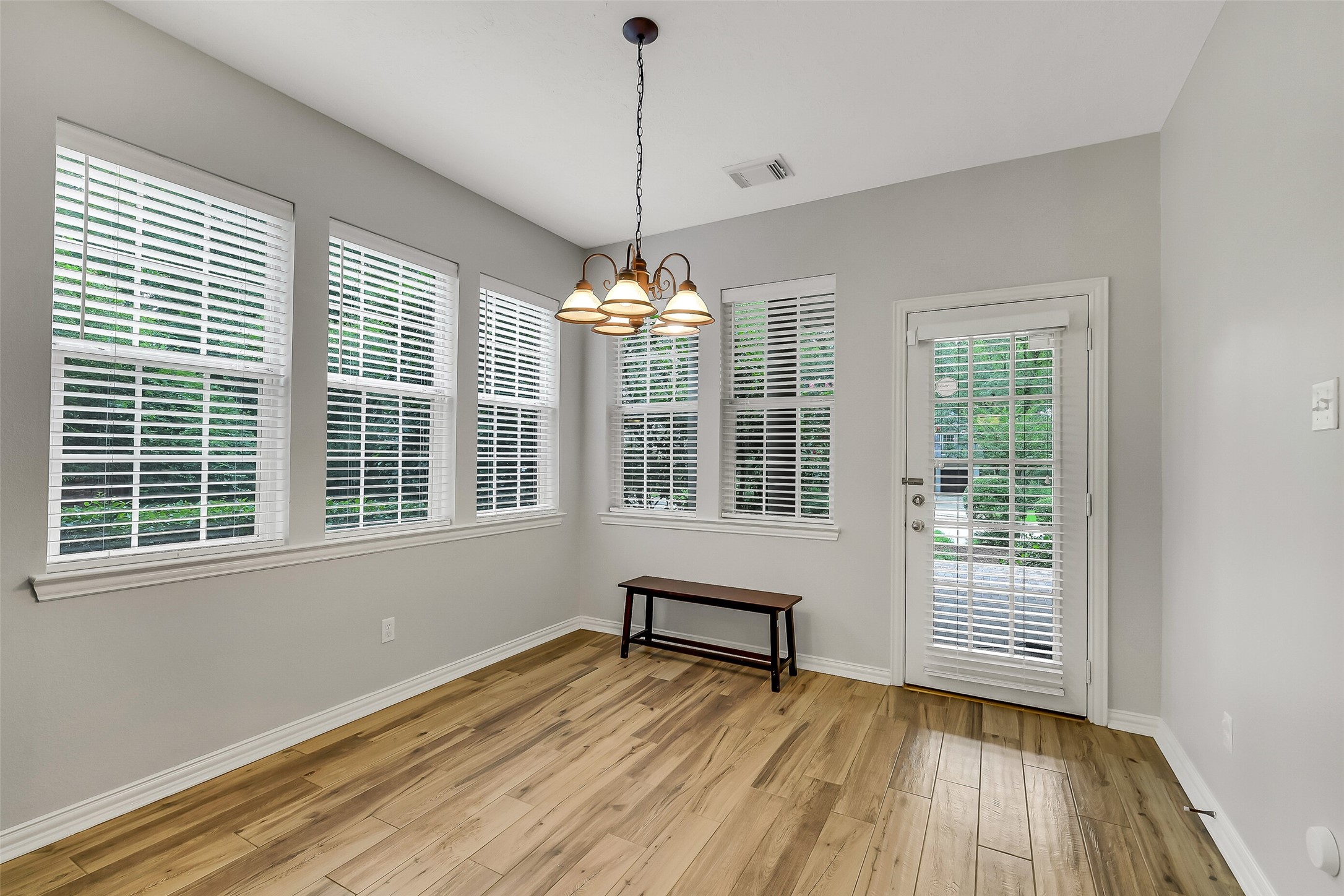 Bright breakfast  area with large windows, elegant light fixture, and beautiful hardwood floors, offering a perfect space for gatherings.