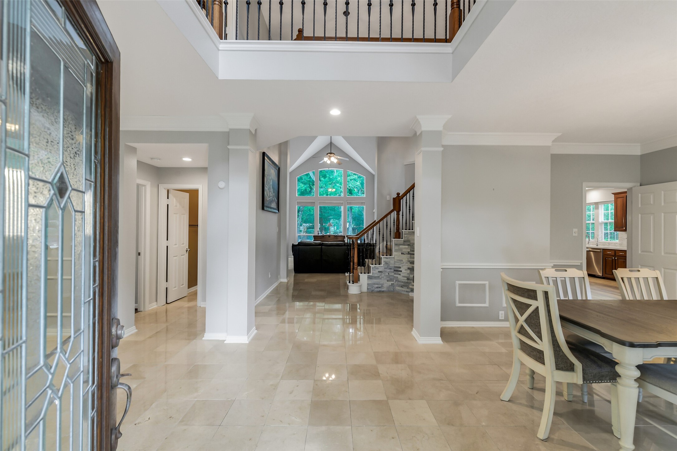 Stunning foyer with high ceilings and elegant tile flooring leads to a spacious living area, featuring a grand staircase and abundant natural light.