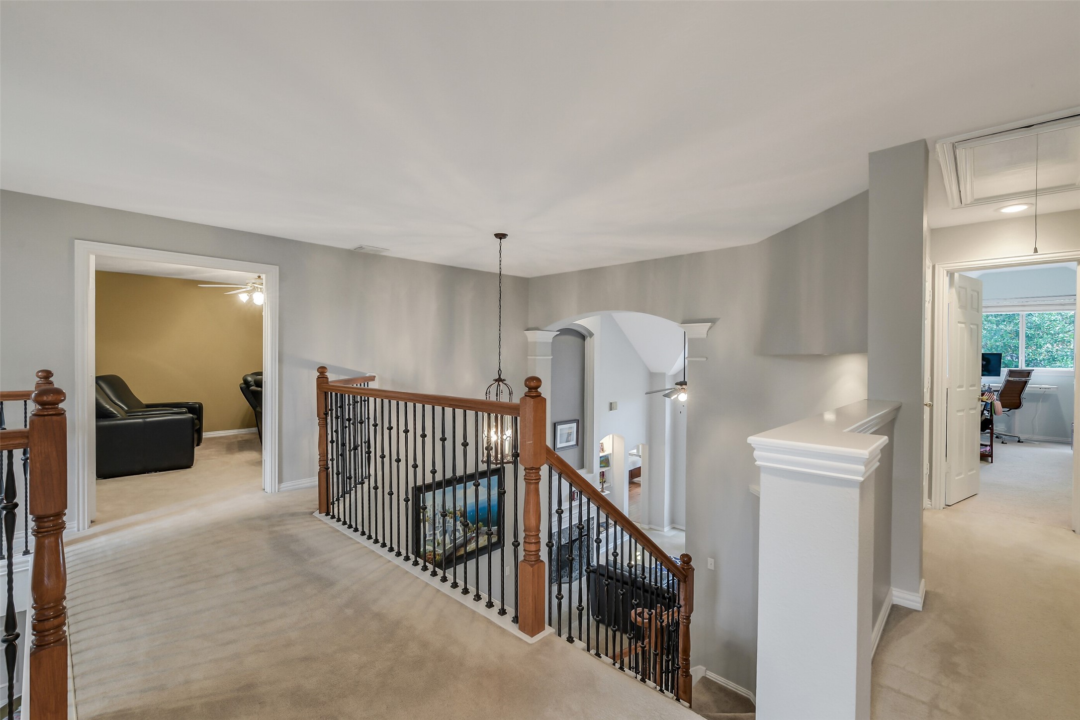 Spacious upstairs landing with elegant wood and iron railing, leading to versatile rooms perfect for a home office or entertainment.