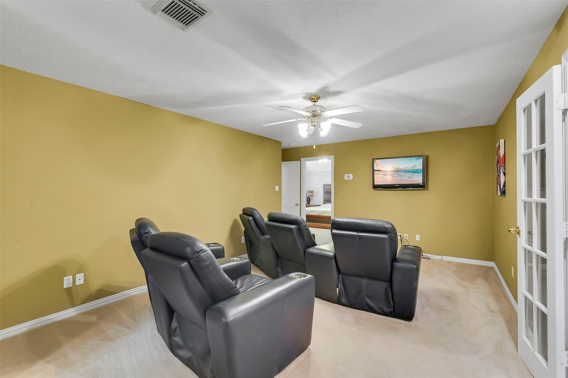 Cozy media room, a ceiling fan, and warm wall tones, perfect for movie nights.