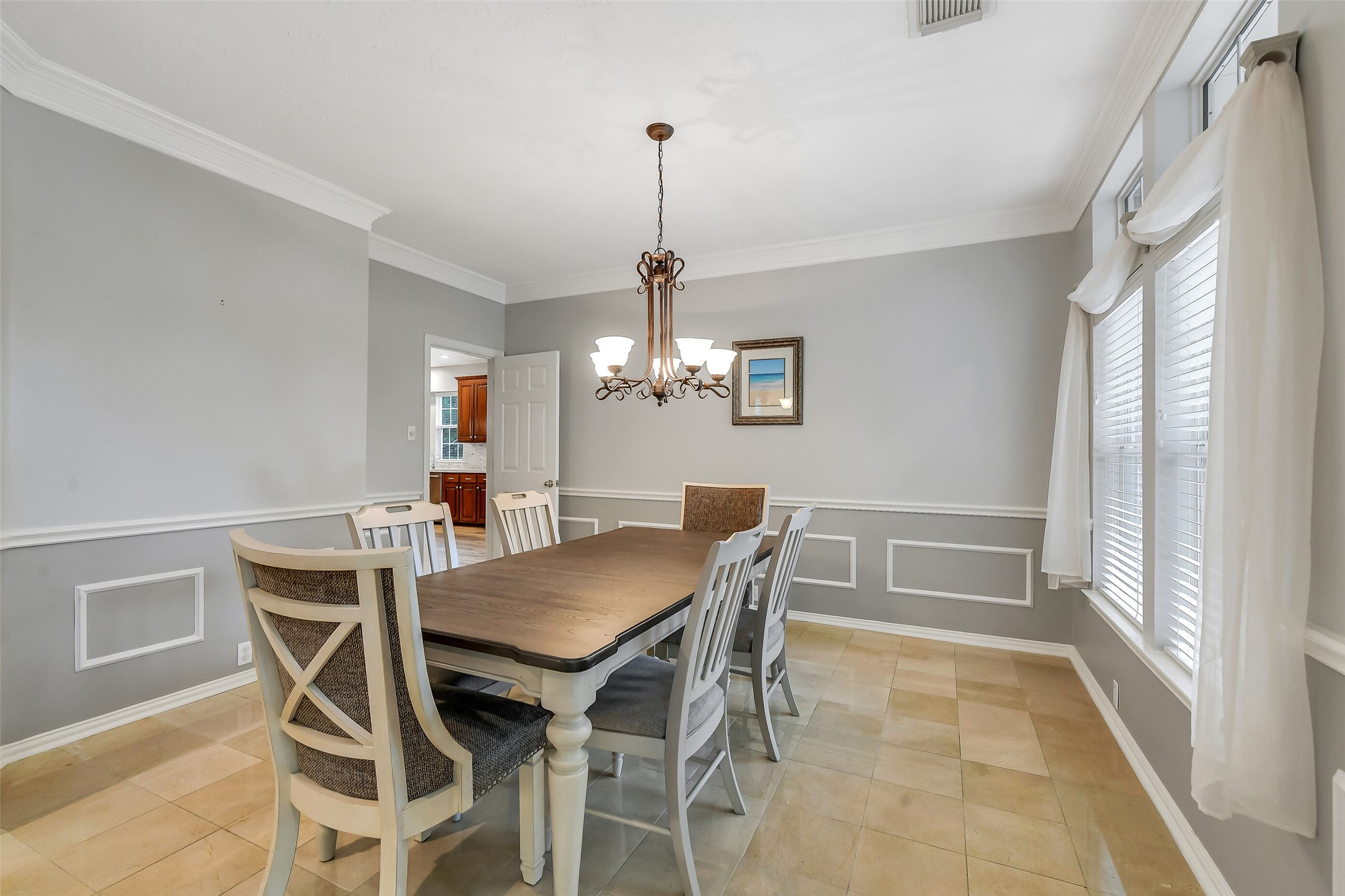 Elegant dining room with a spacious table, stylish chandelier, and large windows that fill the space with natural light.