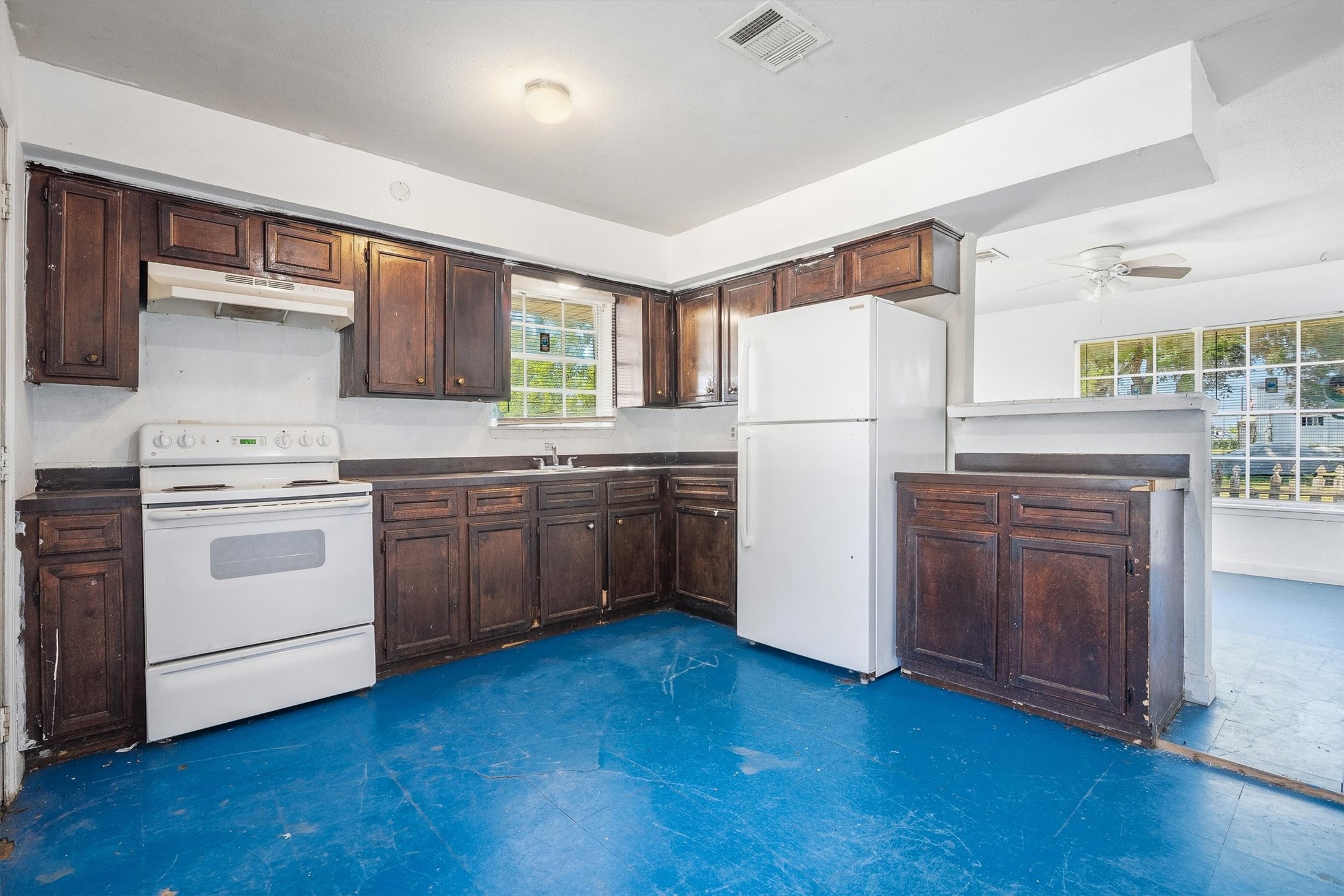 The kitchen showcases rich, dark-stained cabinetry paired with distinctive blue tile flooring, creating a bold contrast and adding character to this functional space.