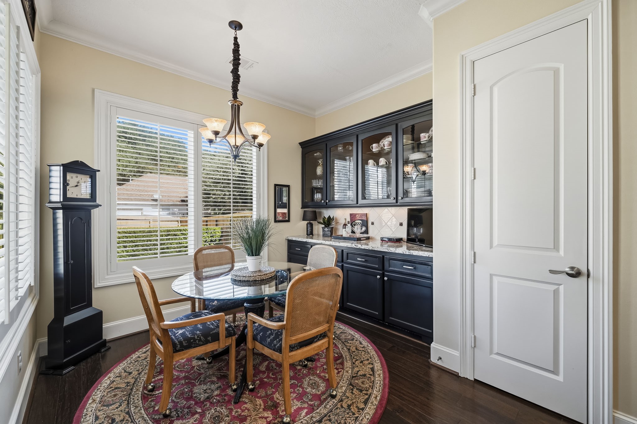 The Breakfast Room is enhanced by a custom built-in Butlers Pantry, thoughtfully designed with rich dark cabinetry, glass-front upper cabinets, a granite countertop, and a decorative tile backsplash. Equal parts beautiful and functional, this versatile space is perfectly suited for a stylish coffee bar, beverage station, or serving area when entertaining. Just beyond, a huge walk-in Pantry offers built-in shelving and abundant storage.