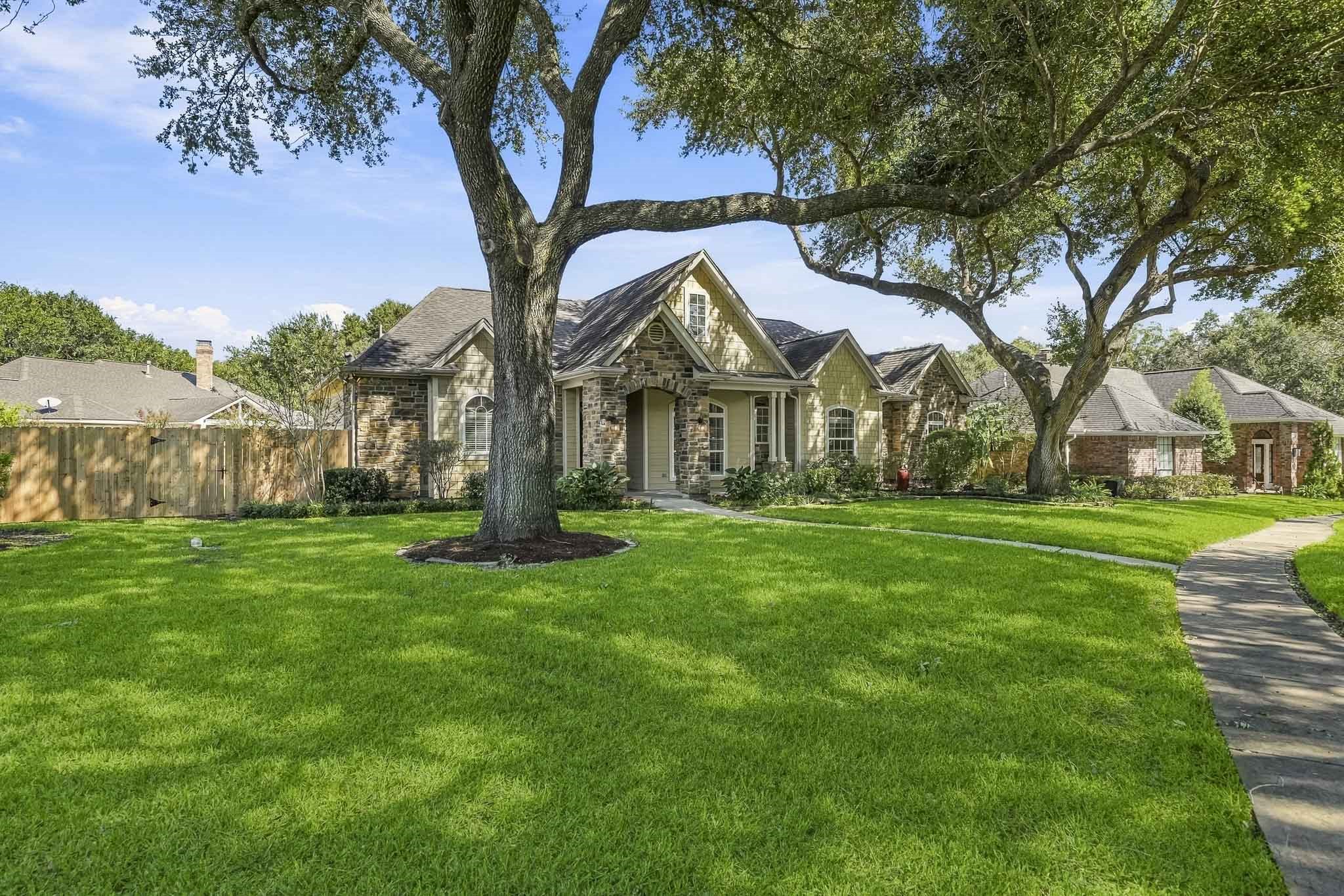 A magnificent pair of mature live oak trees stretches gracefully overhead, creating a lush canopy that blankets the front yard in refreshing, dappled shade. A magnificent pair of mature live oak trees stretches gracefully overhead, creating a lush canopy that blankets the front yard in refreshing, dappled shade.