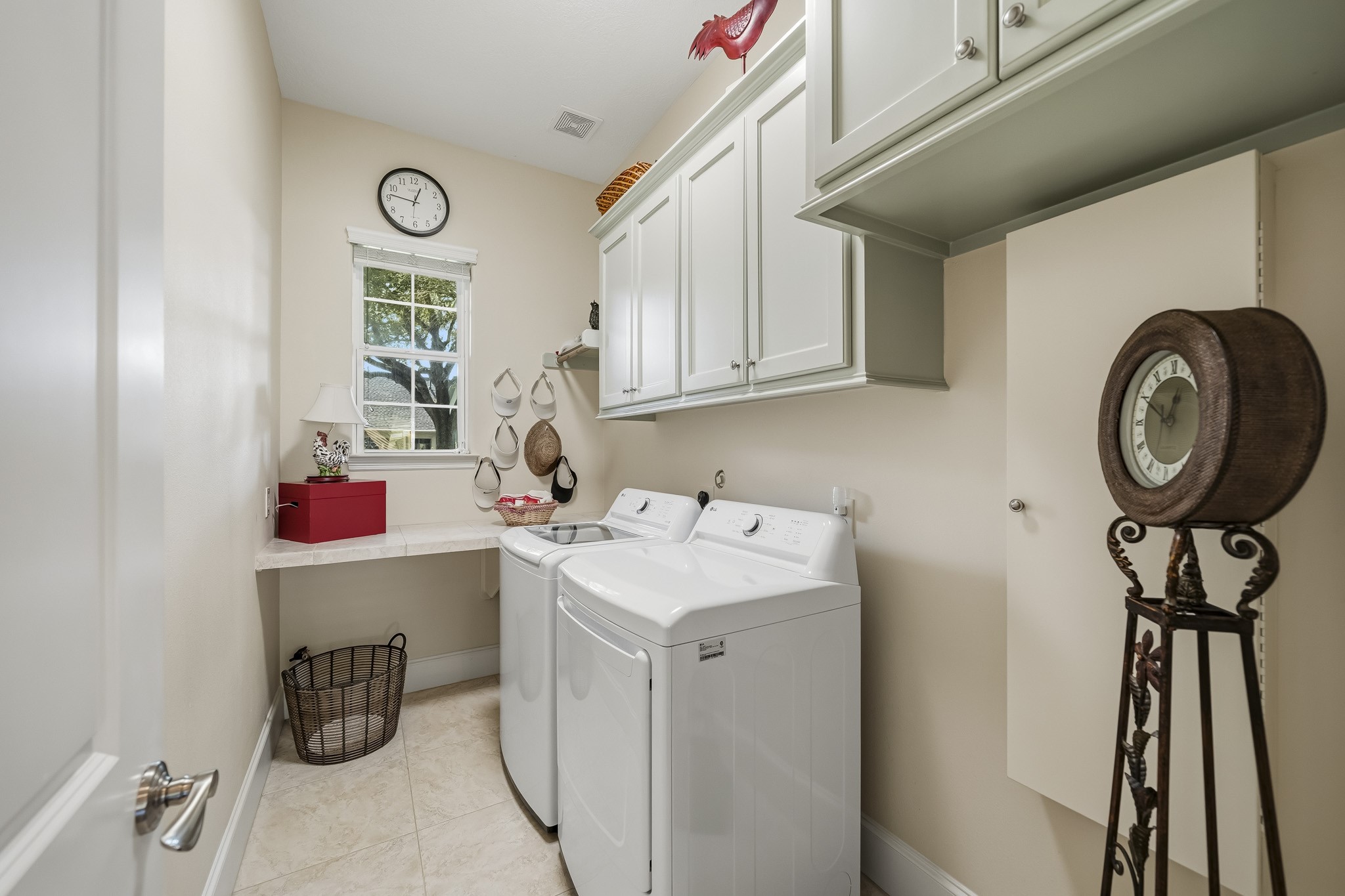This thoughtfully designed Laundry Room transforms everyday chores into a more convenient experience. A spacious countertop provides the perfect area for sorting and folding, while overhead cabinetry keeps detergents, stain removers, and laundry essentials neatly organized and within easy reach. Completing the space is a built-in, pull-down ironing board, offering practical functionality without sacrificing valuable floor space.