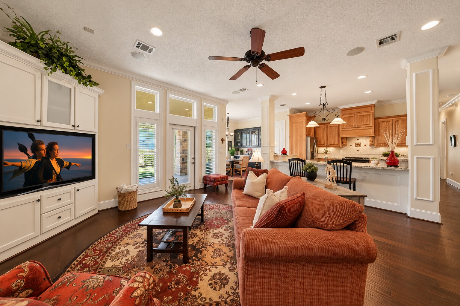 Framed by oversized transoms, a pair of expansive windows bathes the room in natural light, enhancing its bright and inviting atmosphere. A glass-paneled door provides direct access to the covered Back Patio, blending indoor comfort with outdoor living and extending the home's entertaining possibilities.