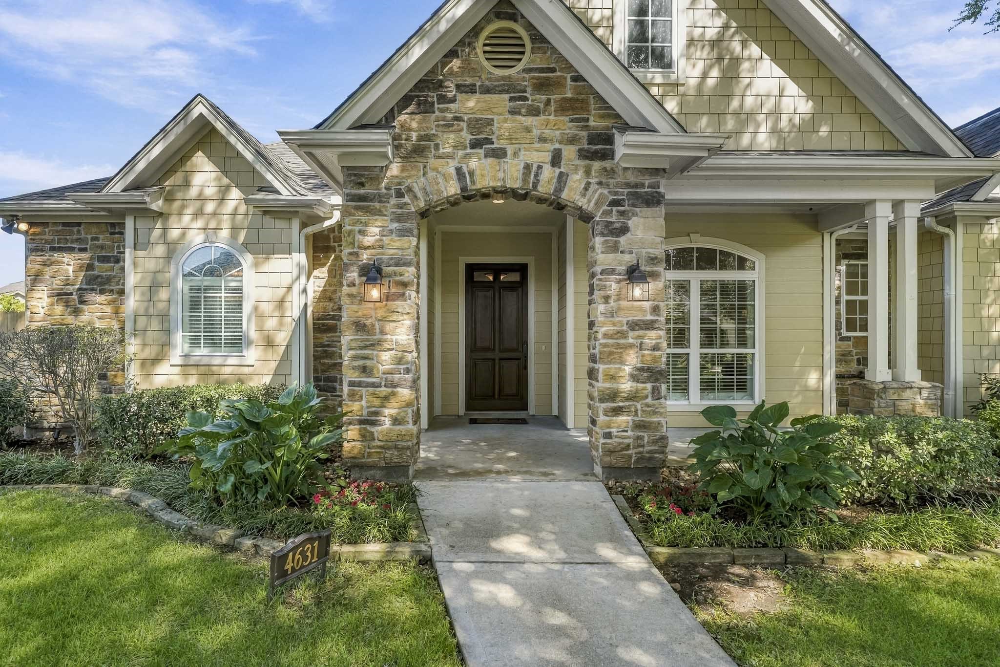 A charming front walkway welcomes guests to the expansive covered porch, where thoughtful landscaping enhances the home's curb appeal. A stone-edged garden bed showcases low-maintenance plants, ornamental grasses, and colorful shrubs, adding texture and visual interest, while a pair of classic lanterns casts a warm, inviting glow. A charming front walkway welcomes guests to the expansive covered porch, where thoughtful landscaping enhances the home's curb appeal. A stone-edged garden bed showcases low-maintenance plants, ornamental grasses, and colorful shrubs, adding texture and visual interest, while a pair of classic lanterns casts a warm, inviting glow.